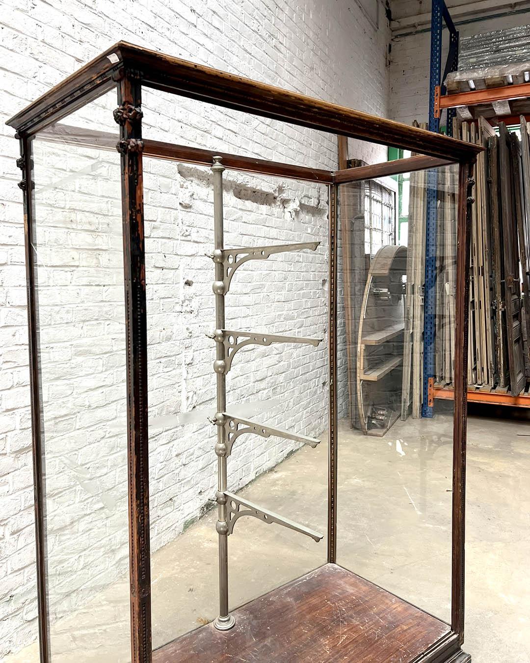 Production palermitaine du début du XXe siècle, this Empire-revival vitrine is crafted in mahogany with delicate carved details and fitted with glass panels on all sides, allowing for full visibility of displayed objects. The central structure