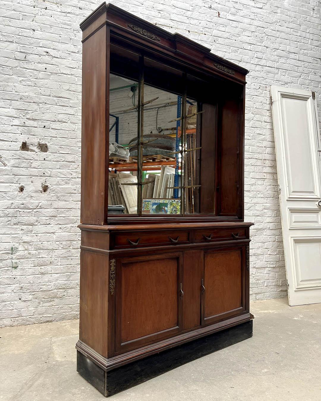 Production palermitaine du début du XXe siècle, this impressive Empire-style vitrine is crafted from mahogany and elm burl, with refined bronze mounts. The structure features two paneled doors in the lower section, surmounted by two drawers and an