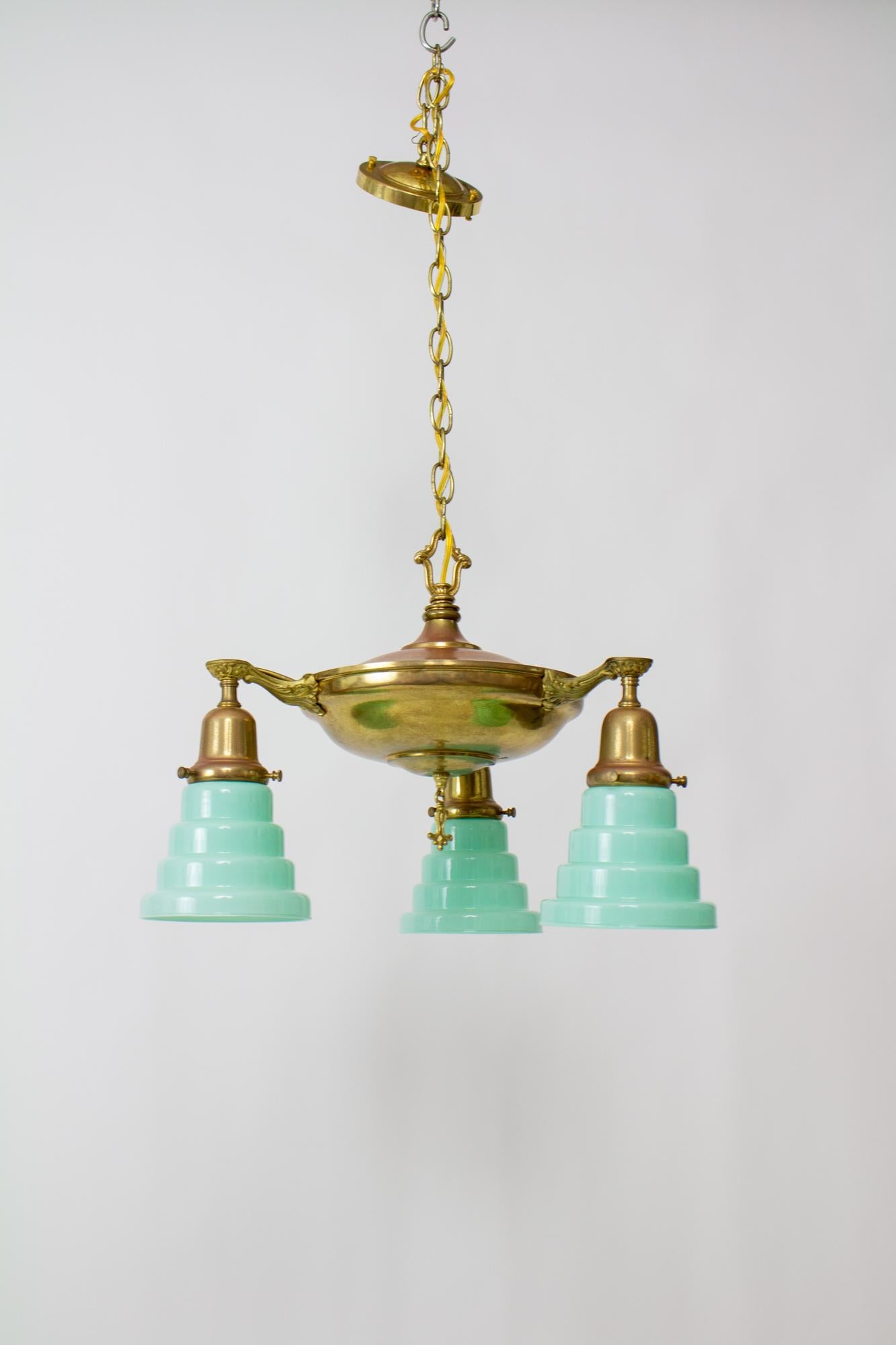 Early 20th century pan light with art deco glass in seafoam green. Classic American three light pan light in an aged brass, with art deco style glass from Vianne of France. An informal fixture with a pop of color. Rewired with chain and canopy.