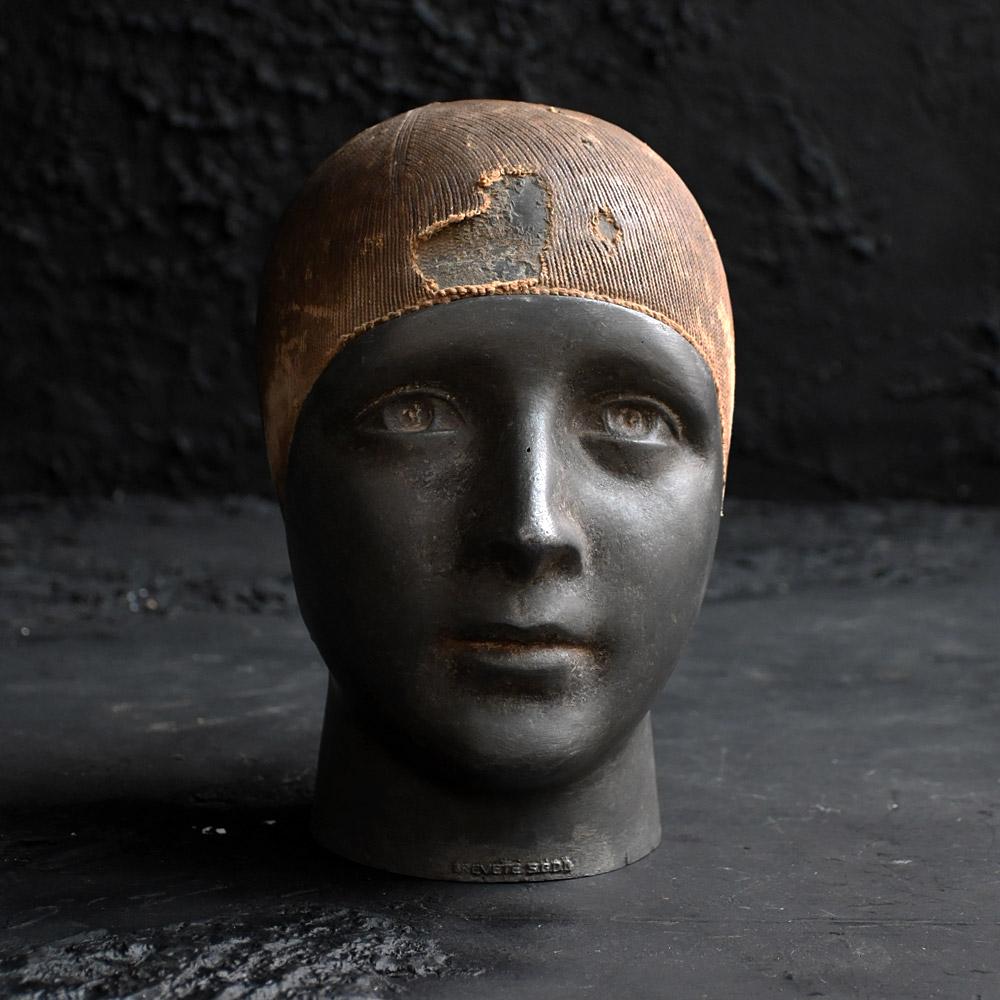 Kopfständer für Perückenmacher aus dem frühen 20.

Gefertigt aus einer gegossenen Metallform in Form eines Frauenkopfes und noch mit dem gut abgenutzten Stützteil aus Stoffgeflecht, an das irgendwann einmal Perücken angeformt wurden. Die Oberflächen