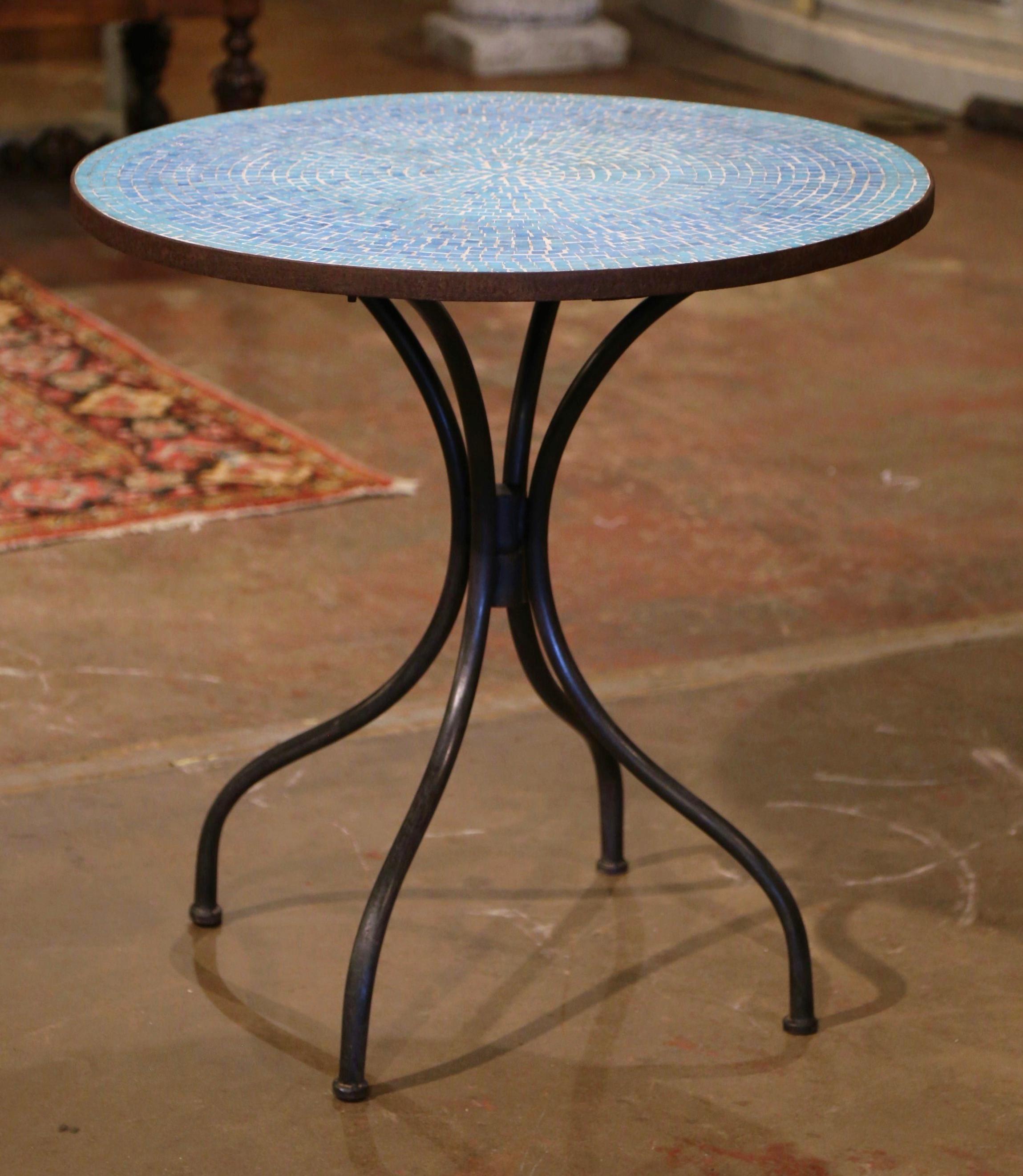 This colorful antique gueridon was crafted in France, circa 1920. The base sits on four scroll legs connected with a central stretcher. The Classic bistrot table is dressed with a circular mosaic top embellished with geometric motifs. The elegant