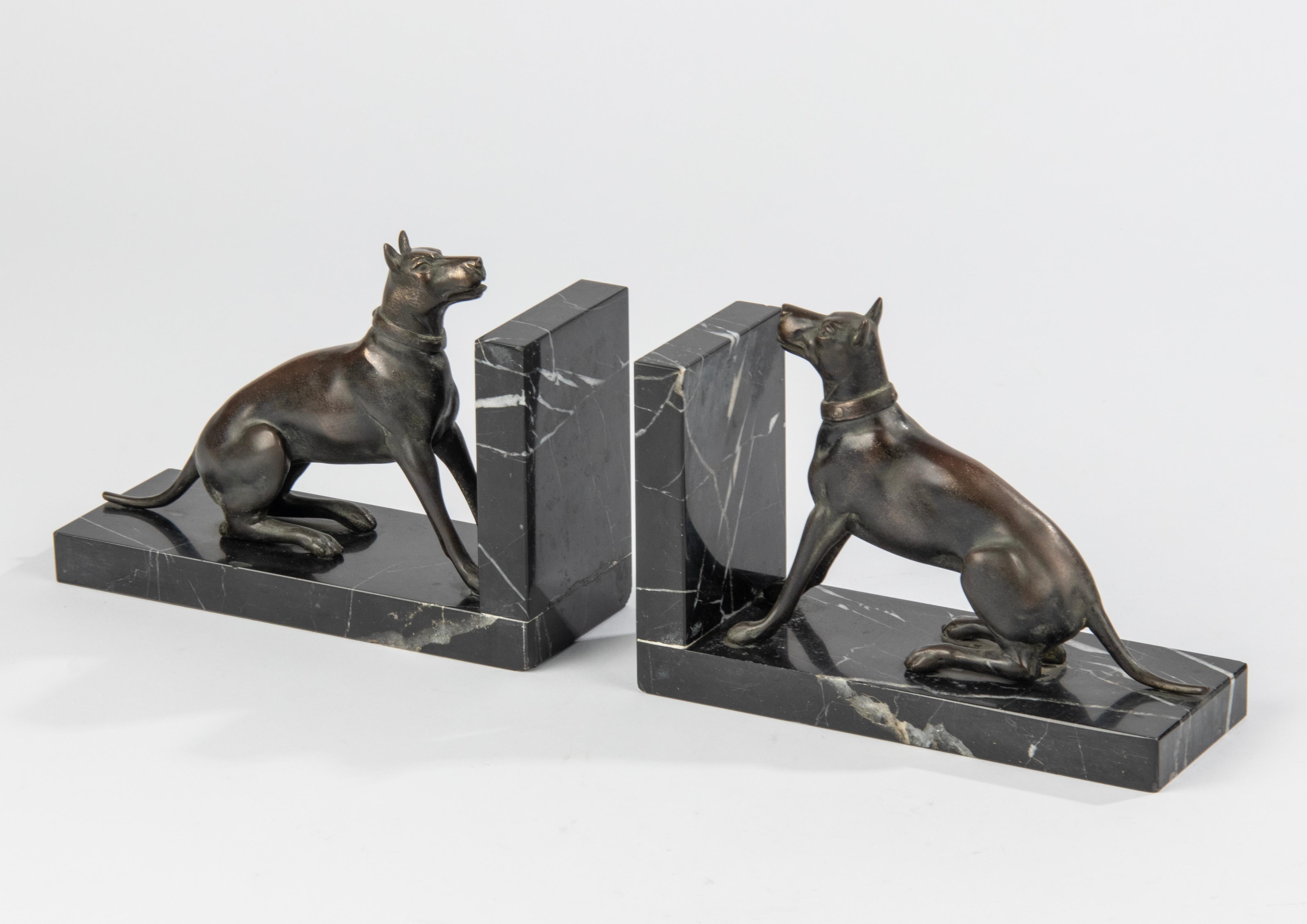 Ein Paar Art Deco Buchstützen mit Skulpturen von Hunden, wahrscheinlich Dansih Hunde. Die Figuren sind aus patiniertem Zinn (Zinklegierung) gefertigt. Die Sockel sind aus schwarzem Marmor mit weißen Adern gefertigt. Marmor und Figuren sind in gutem
