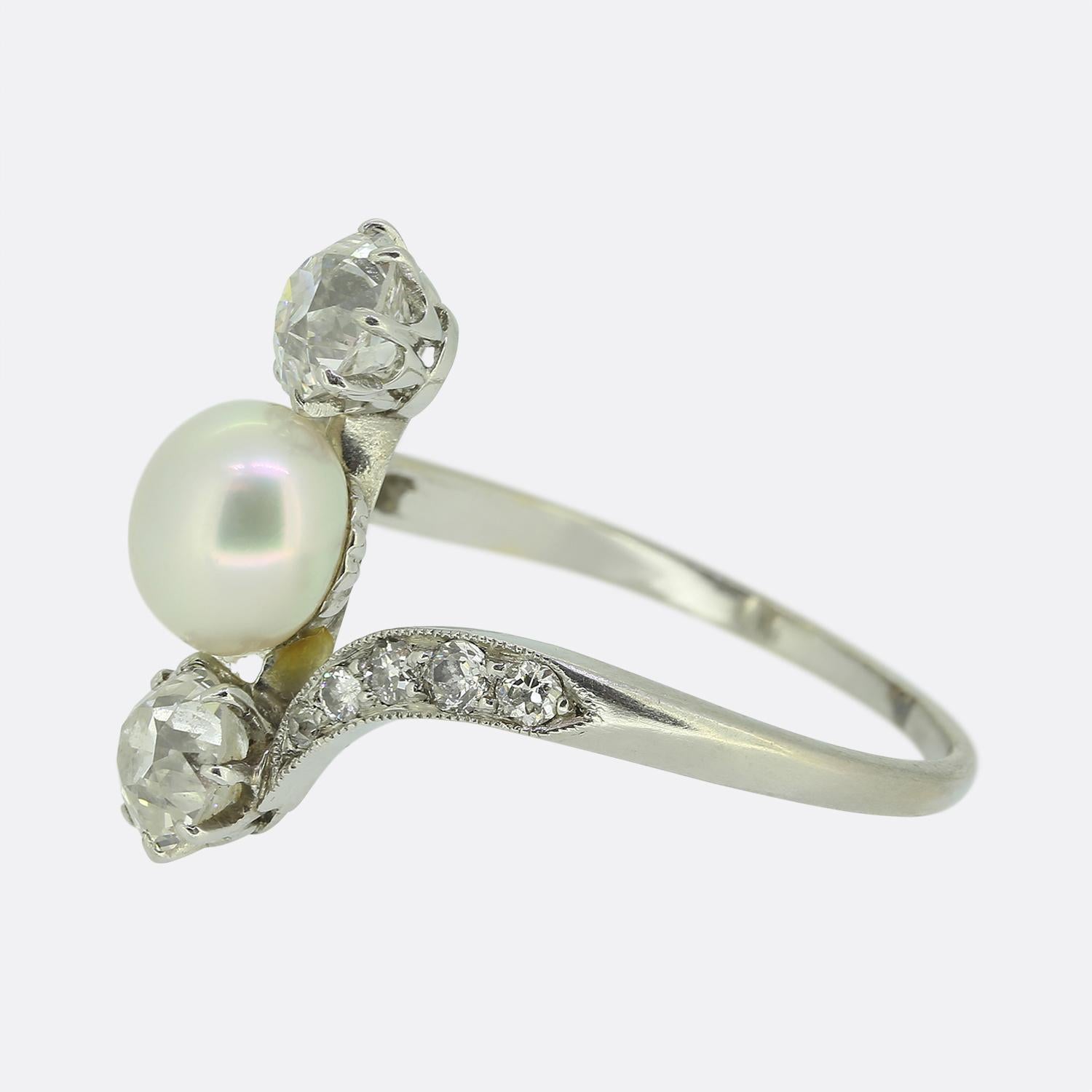 Here we have an exquisite three-stone ring crafted with elegance and precision. This platinum piece features a centralised white button pearl, gracefully complemented by two old mine cut diamonds. The diamonds, set in a sweeping platinum band,