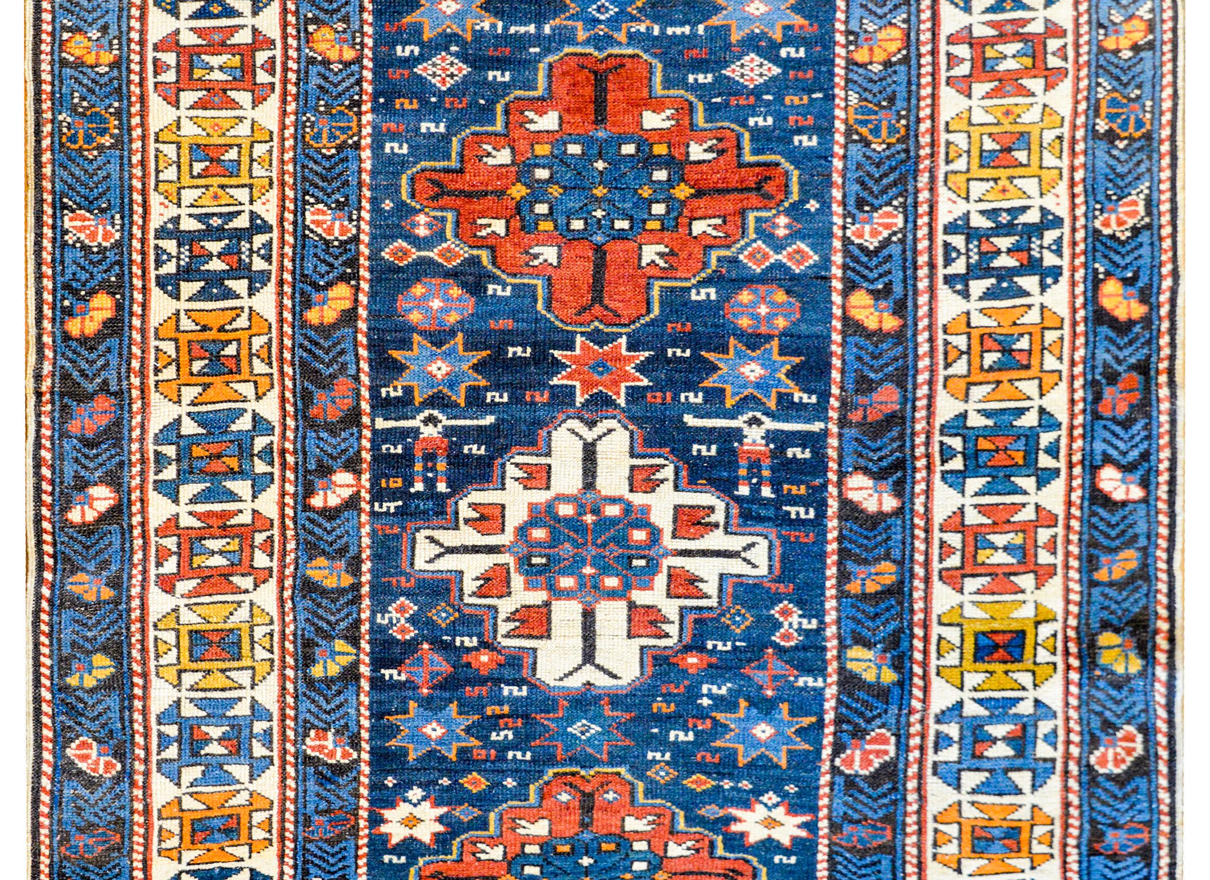 Early 20th century Azerbaijani Shirvan rug with three large stylized floral diamond medallions on an abrash indigo field of stylized flowers surrounded by a wonderful border containing a wide stylized floral patterned central stripe flanked by a