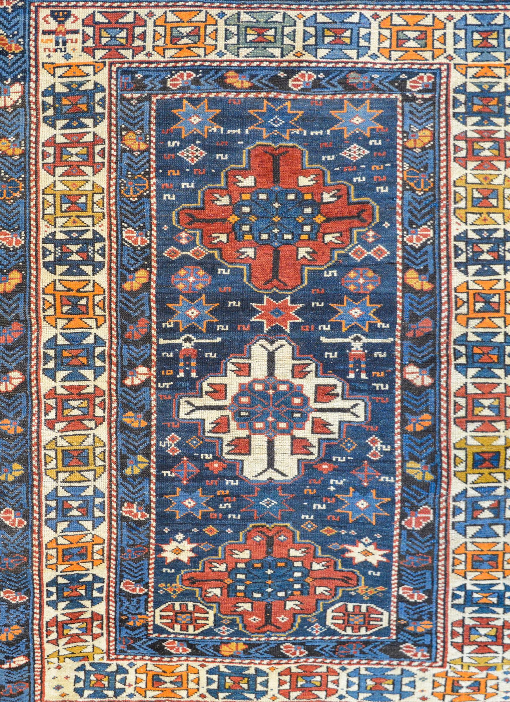 A fantastic early 20th century Azerbaijani Shirvan rug with three diamond medallions, two crimson and one white, on an indigo field of stylized flowers and geometric shapes. The border is exquisite with several stylized floral and vine patterned