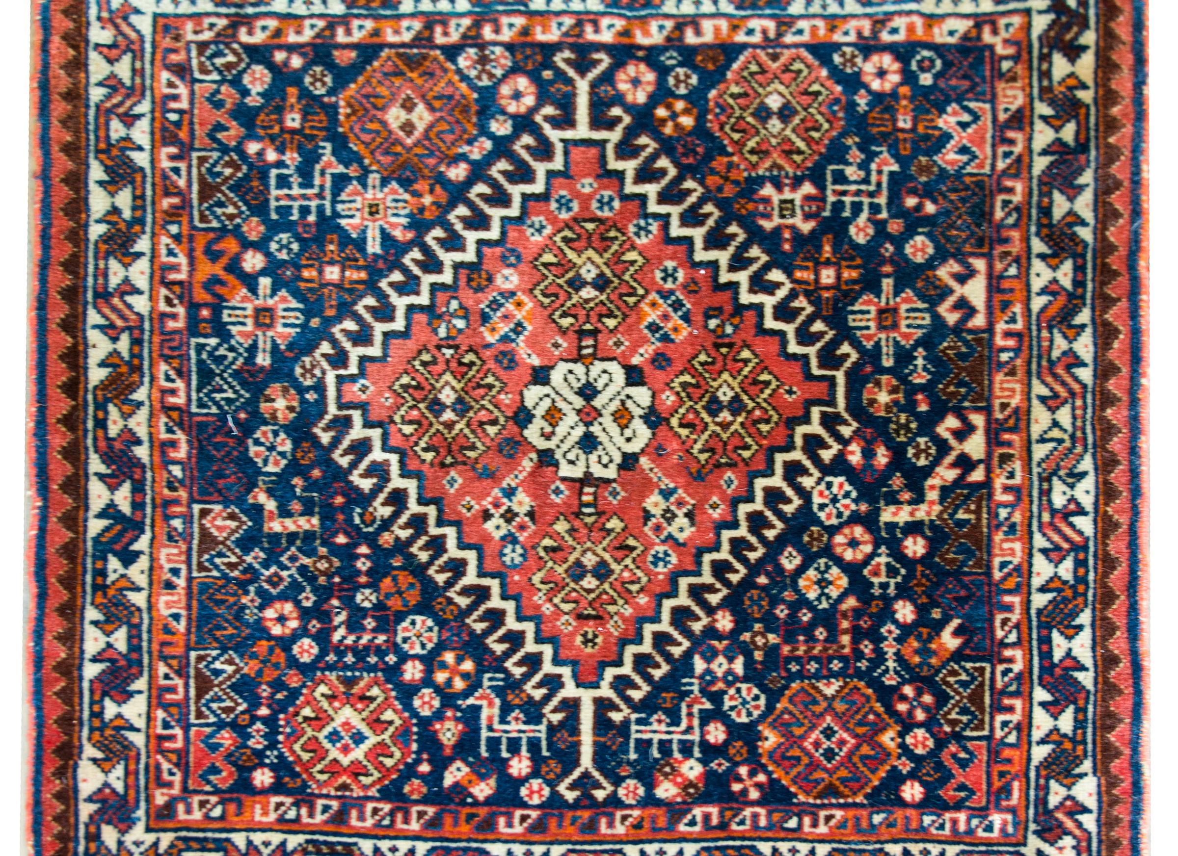 A beautiful early 20th century Persian Afshar rug with a fantastic pattern containing a large central diamond medallion with stylized flowers, and living amidst a field of densely woven petite stylized flowers and goats, all woven in crimson,