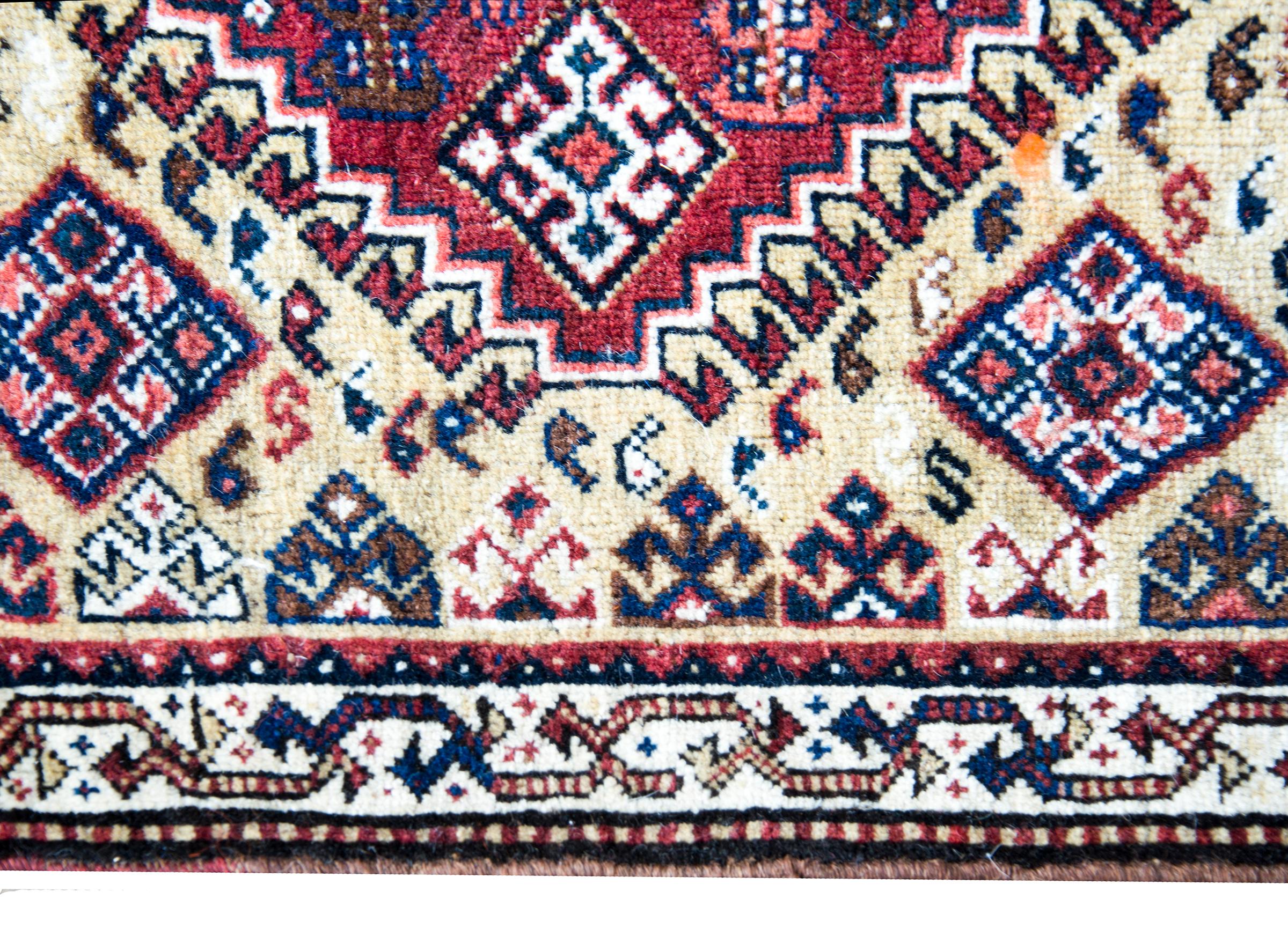 A wonderful early 20th century Persian Afshar rug with a bold tribal pattern with stylized flowers in a diamond medallion amidst a field of more stylized flowers, and surrounded by a floral-inspired border, all woven in crimson, gold, indigo, white,