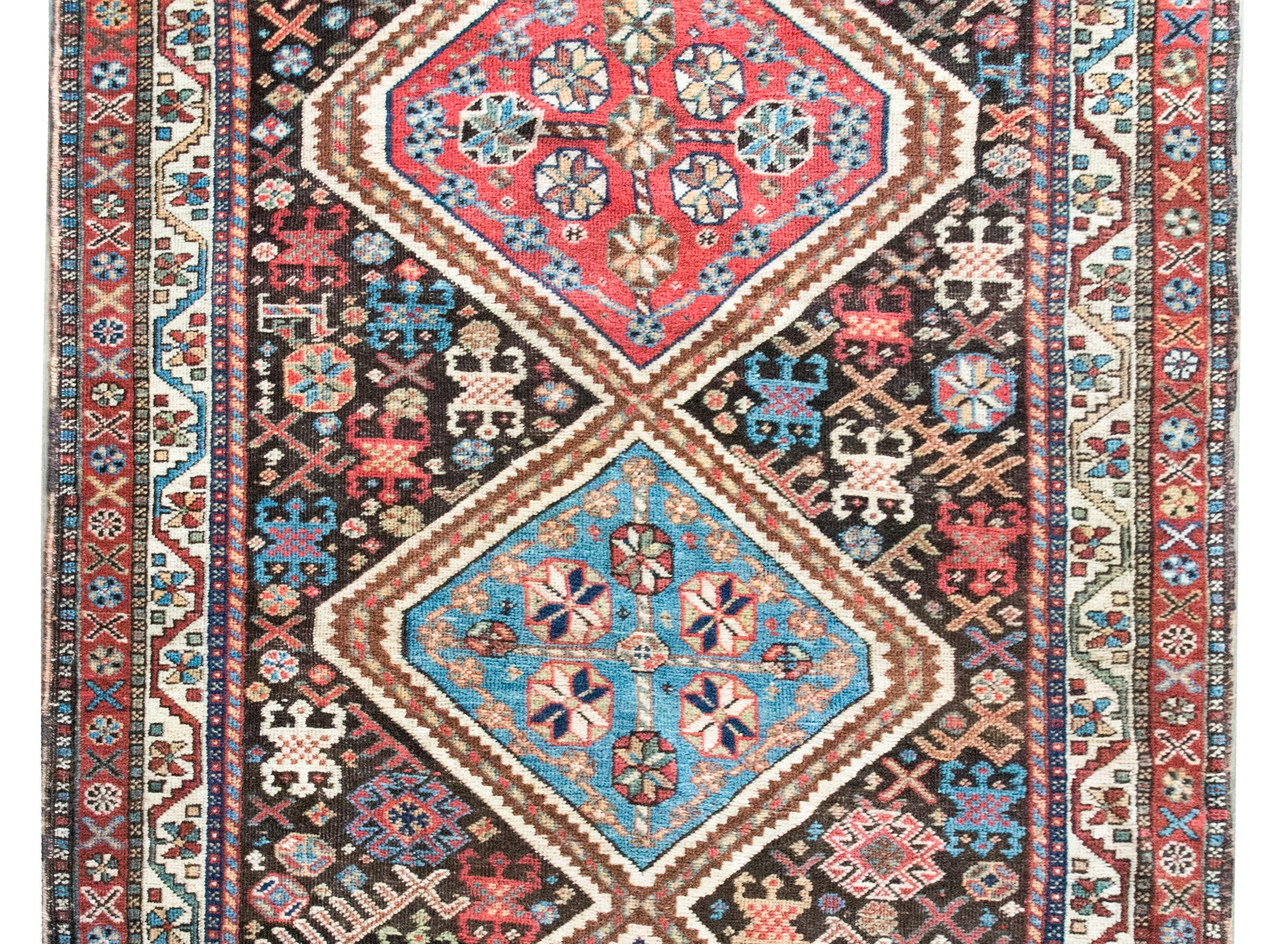 Ein bemerkenswerter persischer Kazak-Teppich aus dem frühen 20. Jahrhundert mit drei großen Rautenmedaillons, die jeweils mit stilisierten Blumen gewebt sind, vor einem Hintergrund mit dicht gewebten Blumen und Tieren, umgeben von einer komplexen