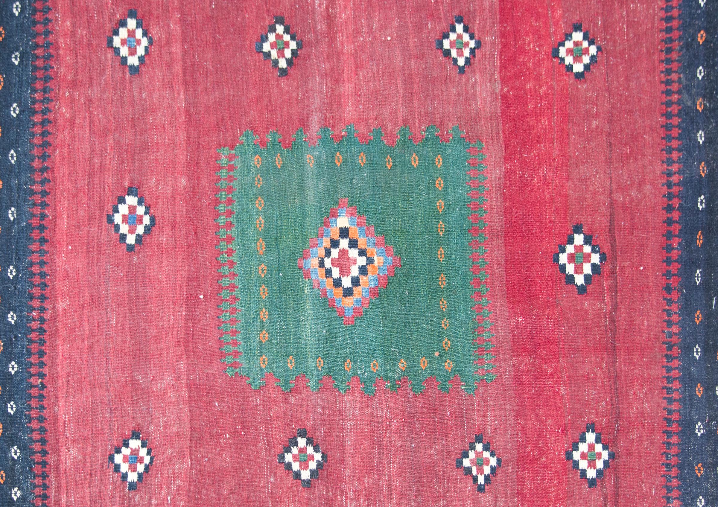 A beautiful early 20th century Persian Afshar Sofreh rug with a geometric pattern with a central multi-colored diamond medallion on a green square living amidst a field of stylized flowers against an abrash crimson background. The border is