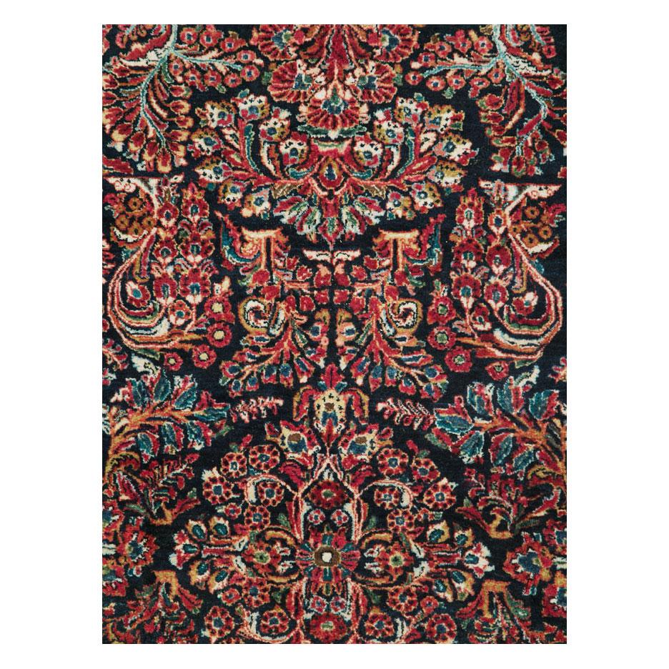 An antique Persian Sarouk accent rug handmade during the early 20th century with a floral design in the 