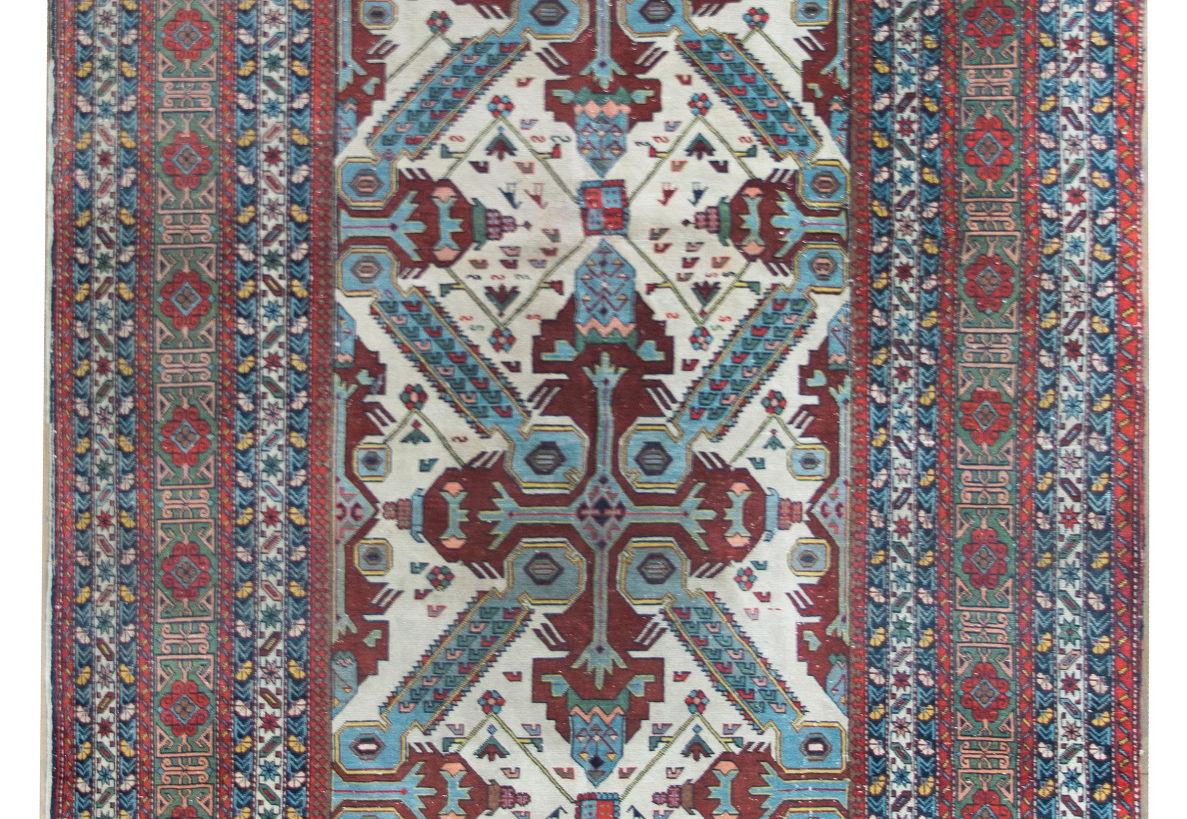 An incredible early 20th century Persian Ardabil rug with a wonderful tribal pattern containing two large medallion with stylized leaves and flowers living amidst a field of petite flowers, and surrounded by a robust complex border composed of
