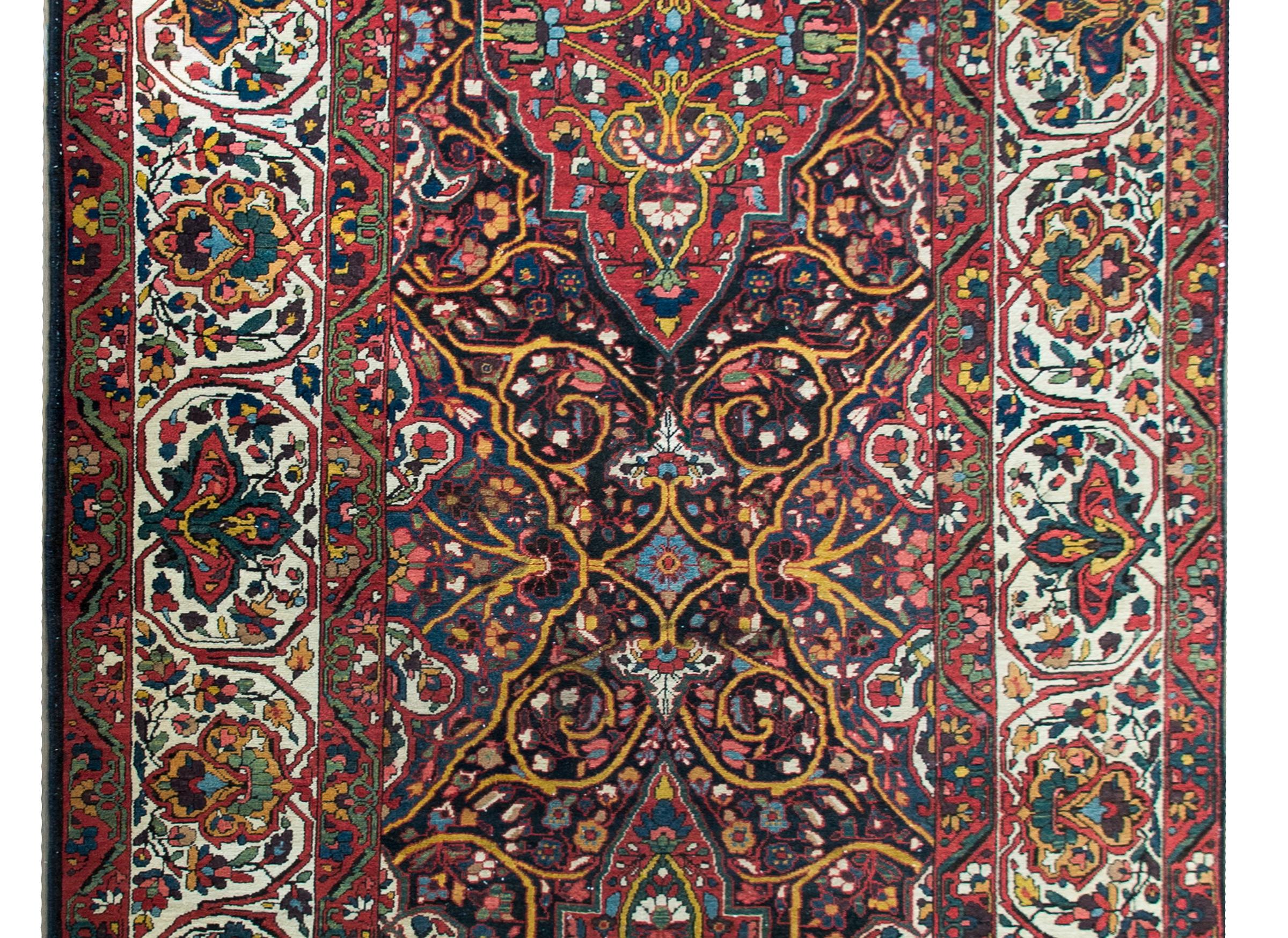 An wonderful early 20th century Persian Bakhtiari rug with two large medallions composed of myriad scrolling vines and flowers woven in a rainbow of colors including crimson, indigo, green, yellow, pink, and white, and surrounded by a wide complex