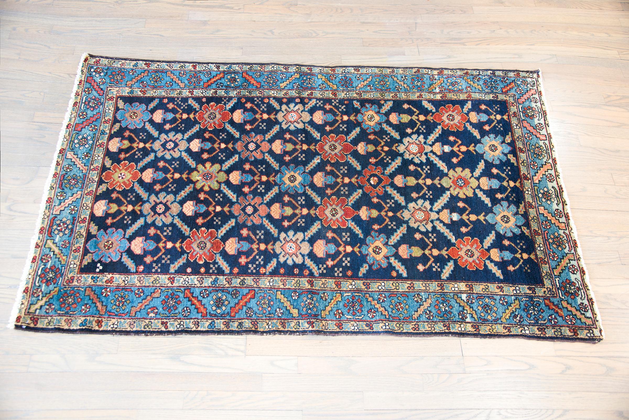 A wonderful early 20th century Persian Bakhtiari rug with a beautiful all-over trellis floral pattern with multi-colored large-scale flowers and leaves set against a dark indigo background, and surrounded by a border with a wide leaf and floral