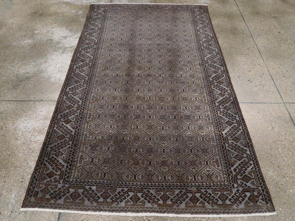 Ein alter persischer Belutsch-Akzentteppich. Ein sehr dichtes sechseckiges Gitter, das geometrische florale Vierpassformen in Anthrazit-, Grau- und Brauntönen einschließt, wird von einer graublauen Bordüre mit schrägen Hakenstäben und kleinen, in