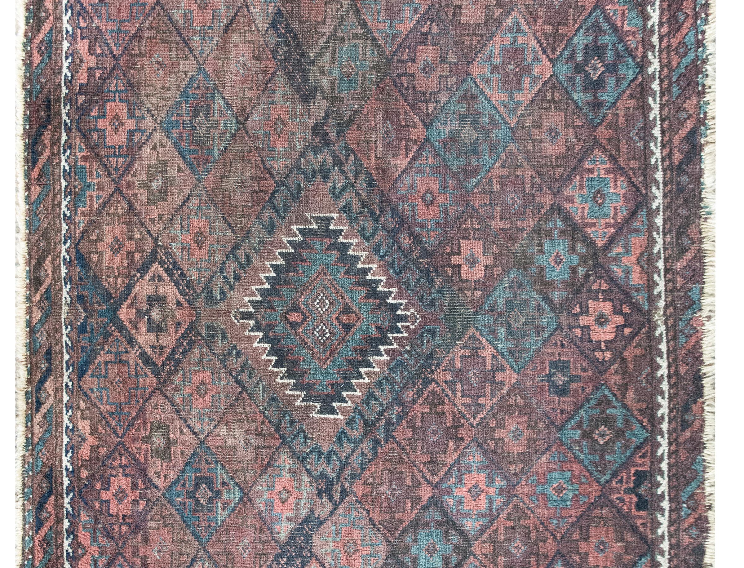 Un elegante e tranquillo tappeto persiano Baluch dell'inizio del XX secolo con un medaglione centrale a diamante circondato da un motivo geometrico di fiori stilizzati a forma di diamante, circondato da un bordo semplice con diverse strisce