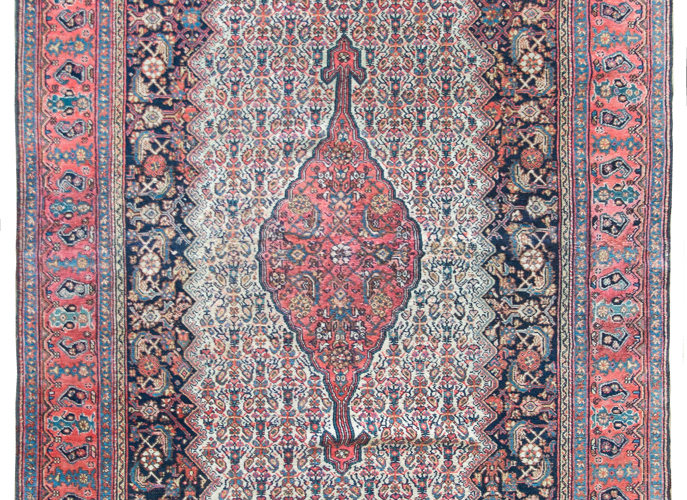 A beautiful early 20th century Persian Bibikibad rug with a large floral patterned medallion living amidst a field of more densely woven flowers, surrounded by a floral border, and all surrounded by a complex border with a wide central floral stripe