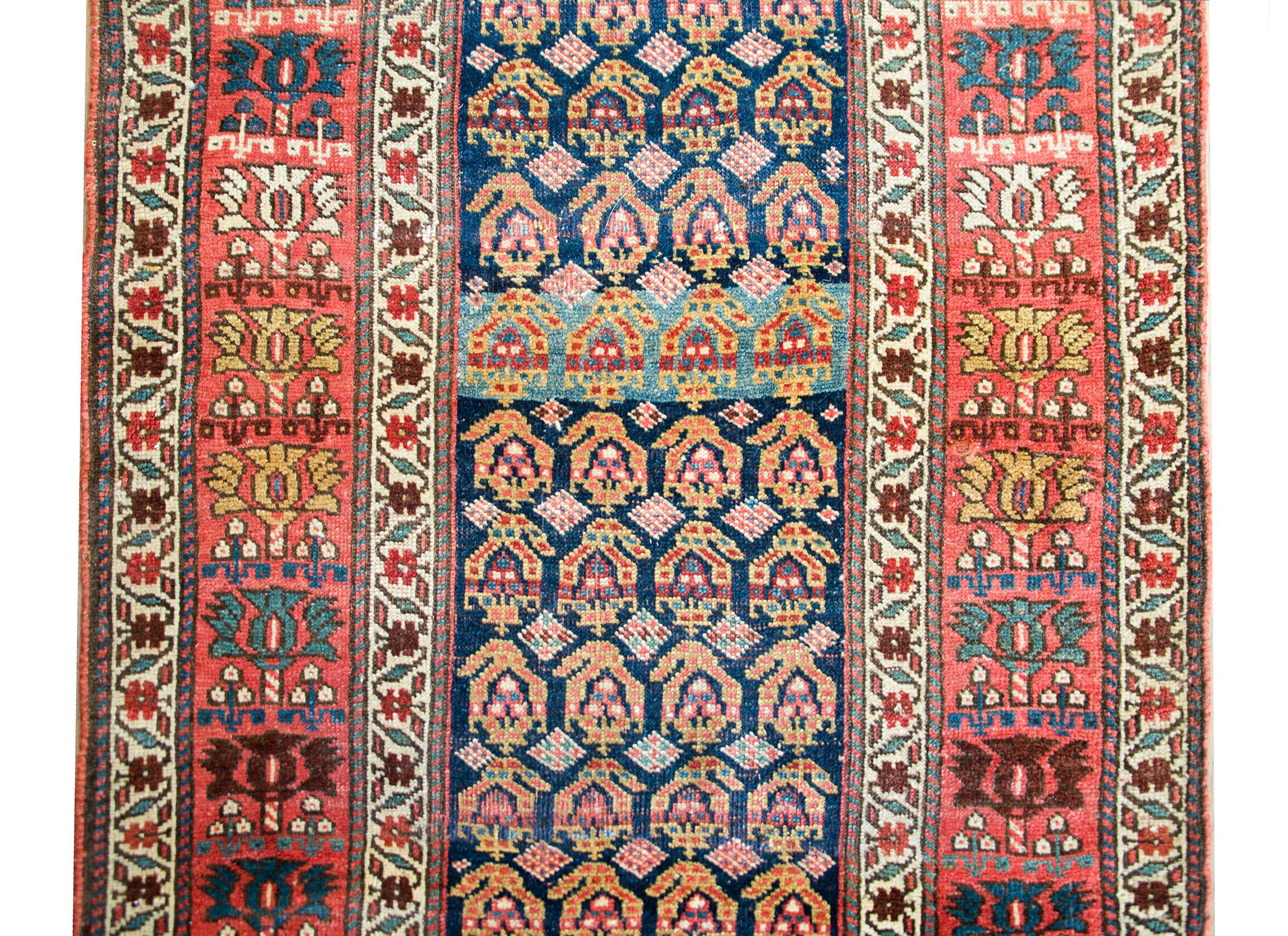 An incredible early 20th century Persian Bidjar runner with an all-over paisley pattern woven in crimson, gold, indigo, and cream, and surrounded by a complex border composed of multiple stylized flowers.