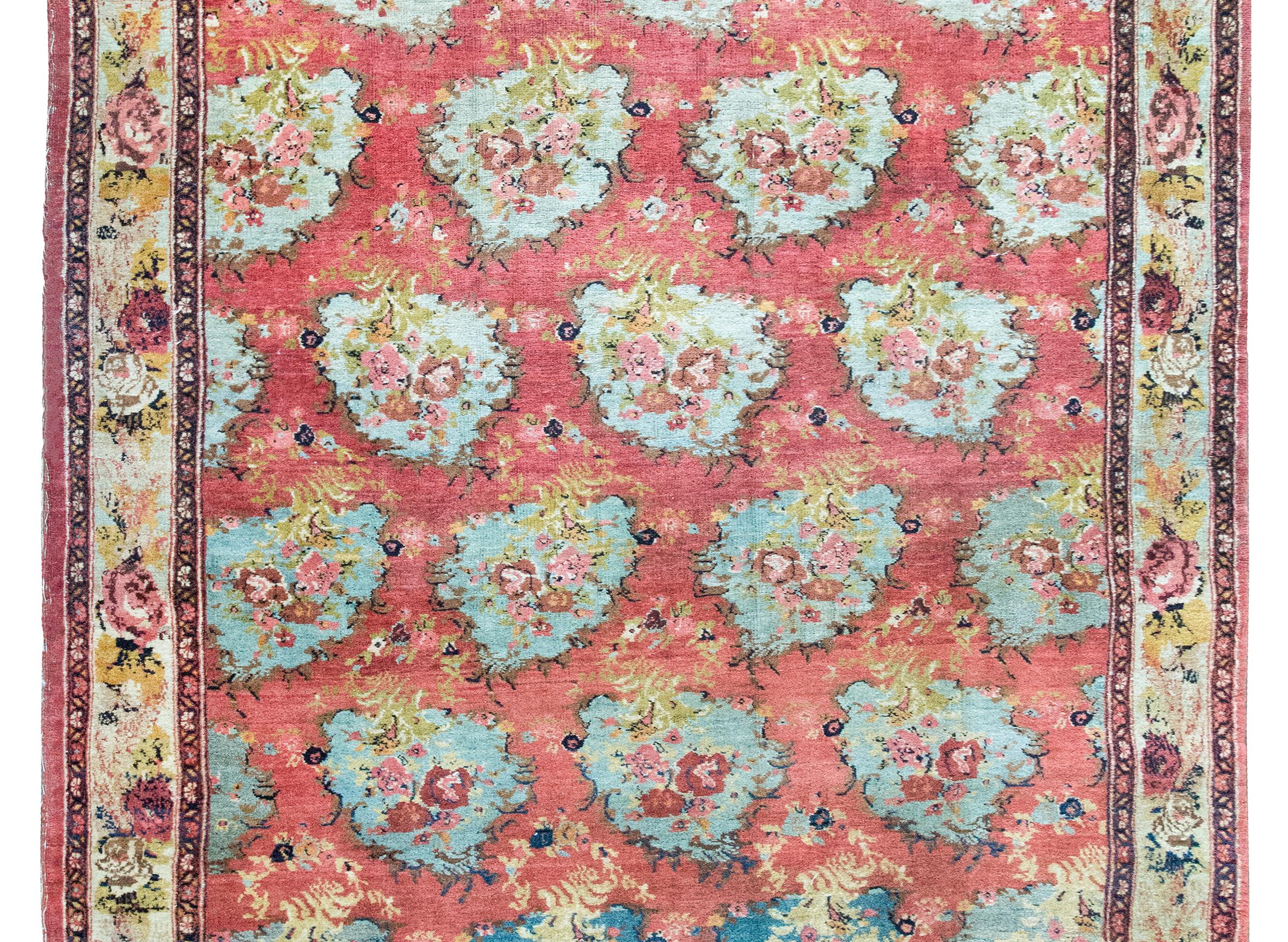 Questo tappeto persiano Bidjar dell'inizio del XX secolo si distingue per il suo design molto insolito: una serie di medaglioni asimmetrici in stile barocco, ognuno dei quali è riempito di rose oversize in rosa tenue e malva, incastonate tra erbe