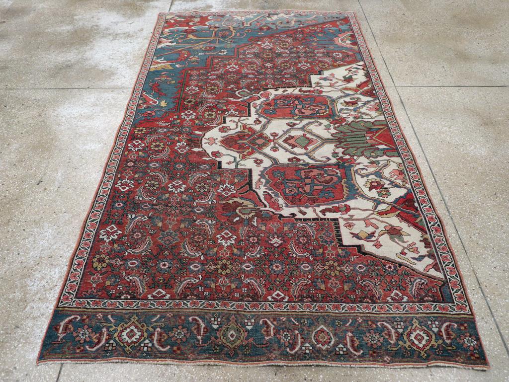 An antique Persian Badjar Sampler rug. This large wagireh (design sampler) shows half an ivory medallion with interior palmettes, a rose-red Herati field pattern and a cerulean blue corner with broad yellow arabesques. The border snippet at the top