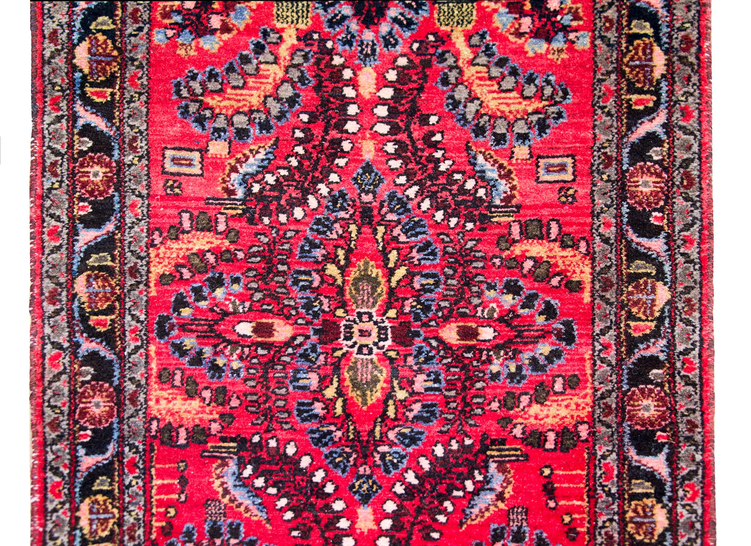 A wonderful early 20th century Persian Dargazin rug with a mirrored floral pattern with myriad floral and leaf clusters covering the field, surrounded by a simple border comprised of three thin petite floral patterned stripes, and all woven in