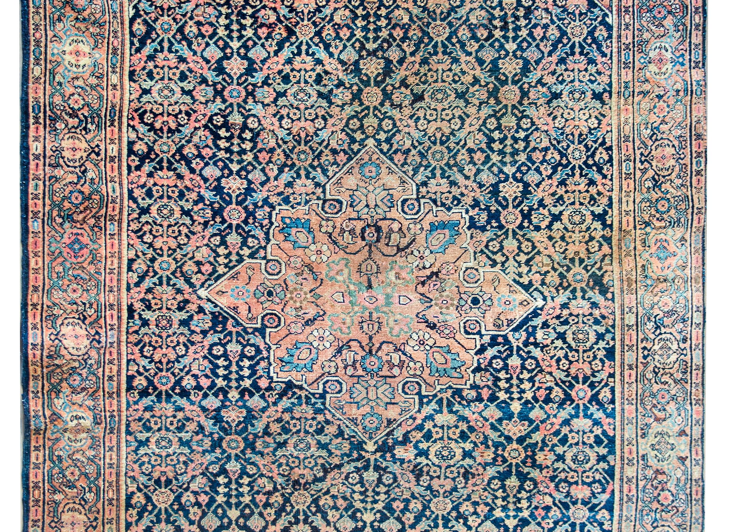 A remarkable early 20th century Persian Farahan rug with a traditional Herati pattern containing a large central floral medallion living amidst a floral trellis pattern background with myriad flowers and leaves, and all woven in salmon, indigo,
