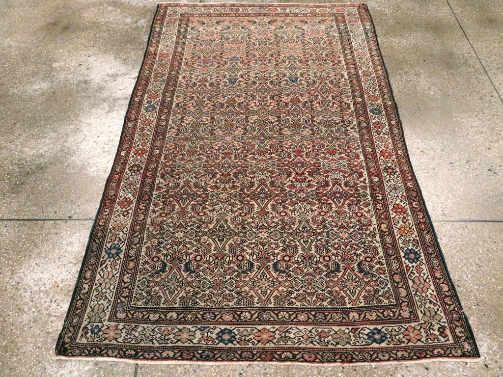 An antique Persian Fereghan accent rug. This is an antique rug with a dense allover Herati pattern of leaves, lozenges, and rosettes very closely covering the pale straw ground, all within an ivory rosette and stiff linking vine border. The weave is
