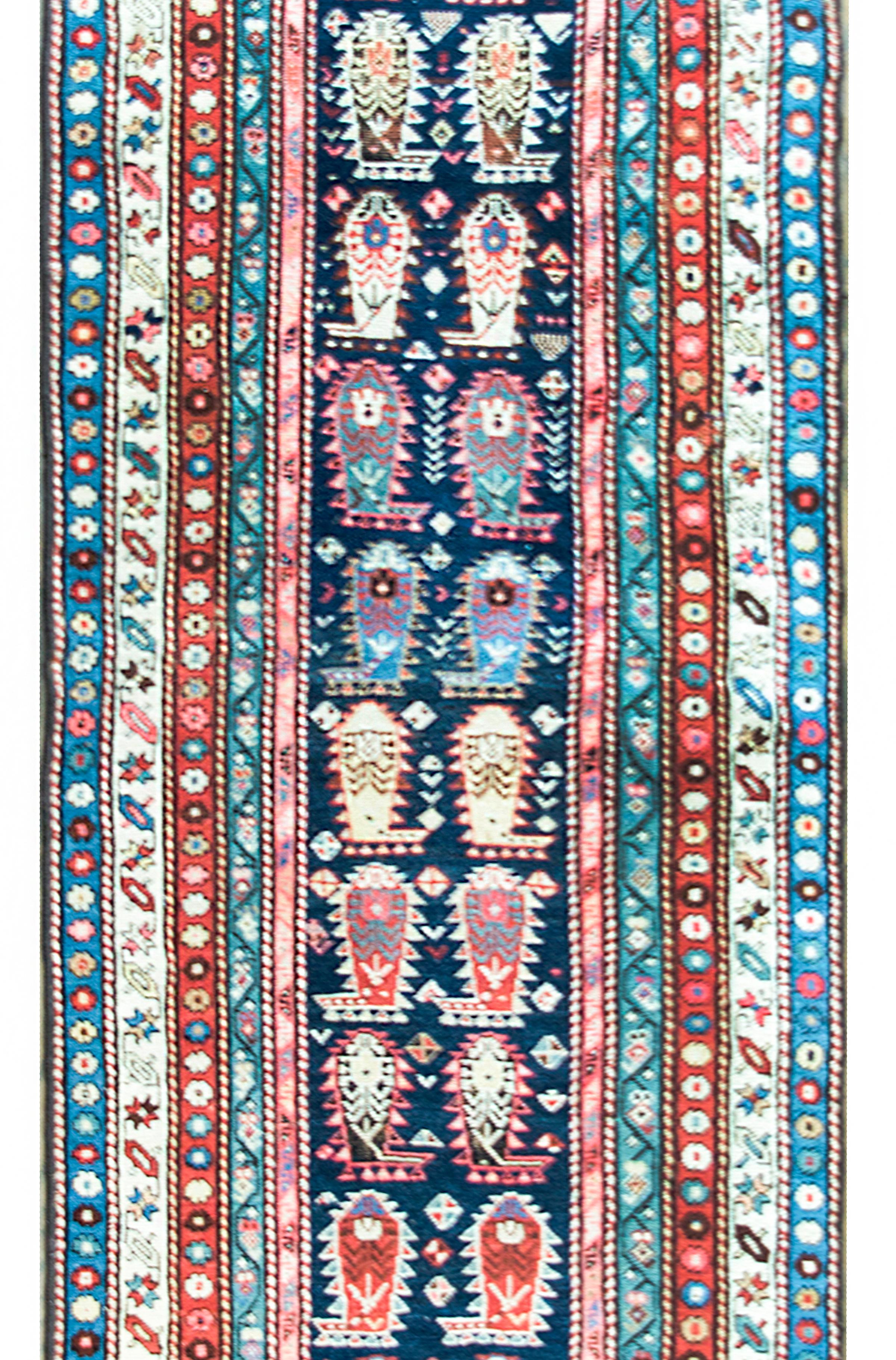 A stunning early 20th century Persian Ganjeh runner with an all-over repeated paisley pattern surrounded by a wide border with multiple petite floral patterned stripes, and all woven in bright cimrsons, indigos, golds, pinks, and cream colored wools.