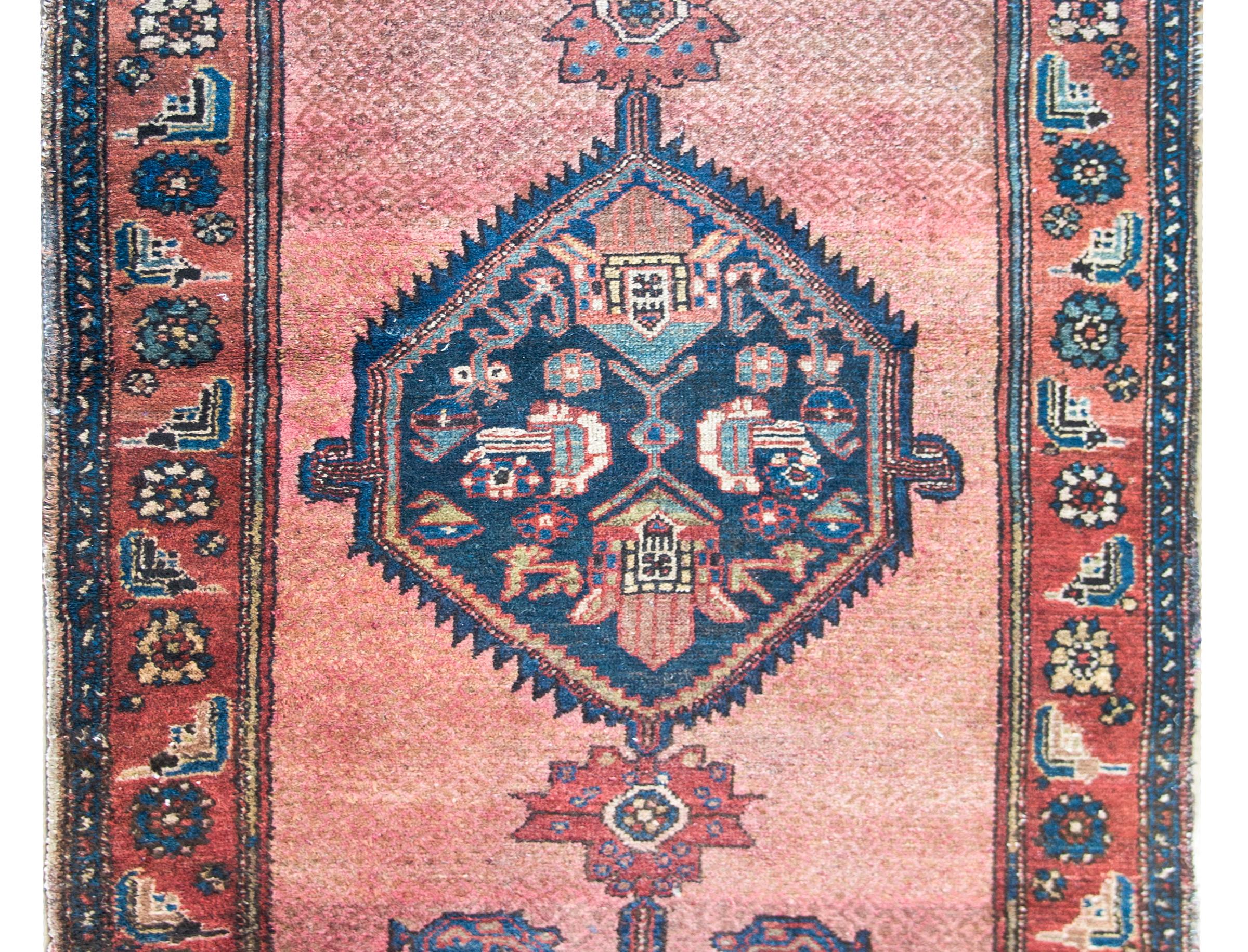 Preciosa alfombra persa Hamadan de principios del siglo XX con un maravilloso medallón central en forma de rombo lleno de flores estilizadas, flanqueado por más flores, y todo ello sobre un campo carmesí pálido con un sencillo fondo de pequeños