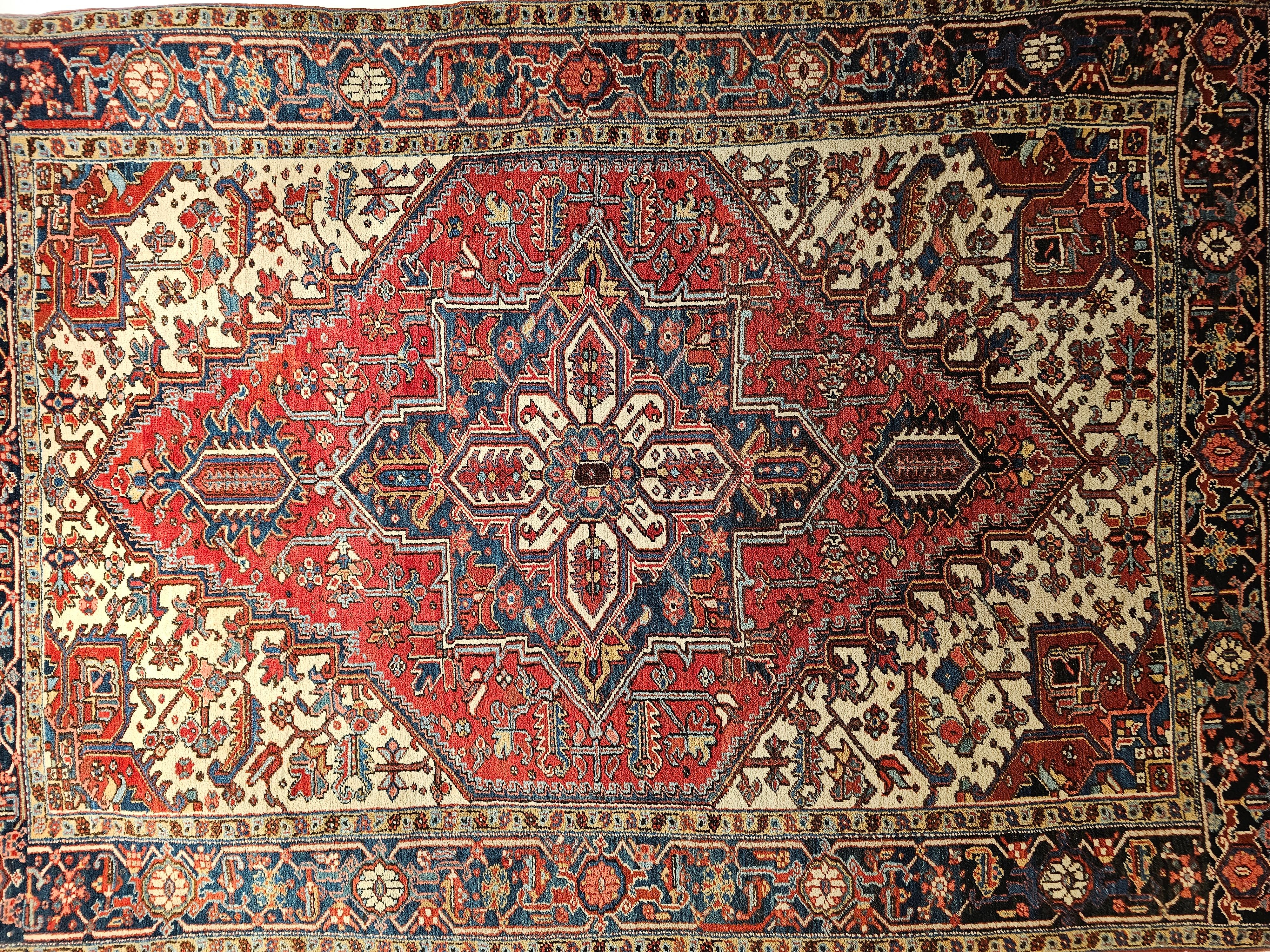 Room size Persian Heriz rug from the first quarter of the 20th century comes with a nice ivory color in the corners and red color in the center and blue in the border which is a great combination. The rug is in the smaller room-size Heriz which is