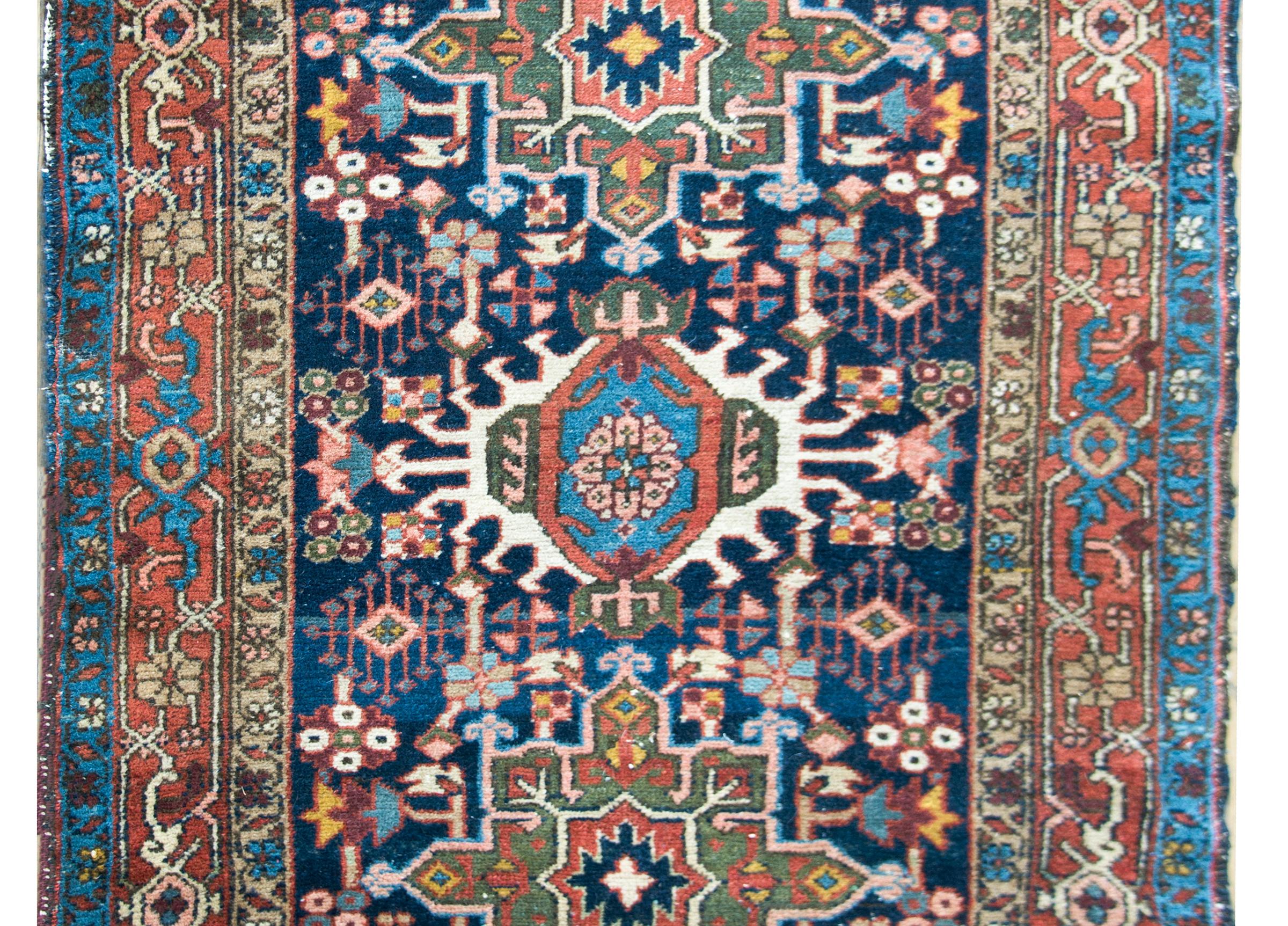 A beautiful early 20th century Persian Heriz rug with three large stylized floral medallions amidst a field of more densely woven flowers, and surrounded by a border with three distinct floral and scrolling vine patterned stripes.