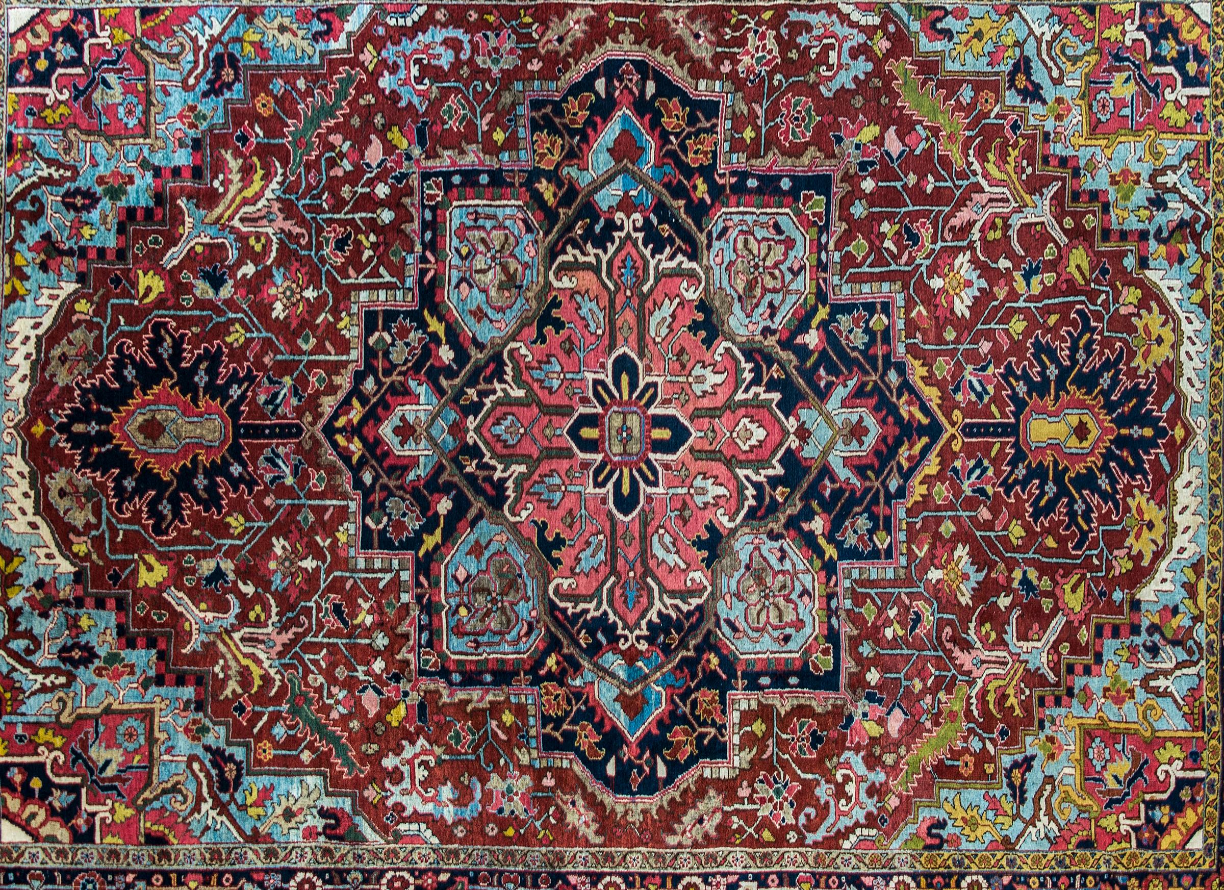 A gorgeous early 20th century Persian Heriz rug with a fantastic large eight-lobed floral medallion, living amidst a field of scrolling vines and leaves, surrounded by a complex wide floral and leaf border, and all woven in myriad colors including