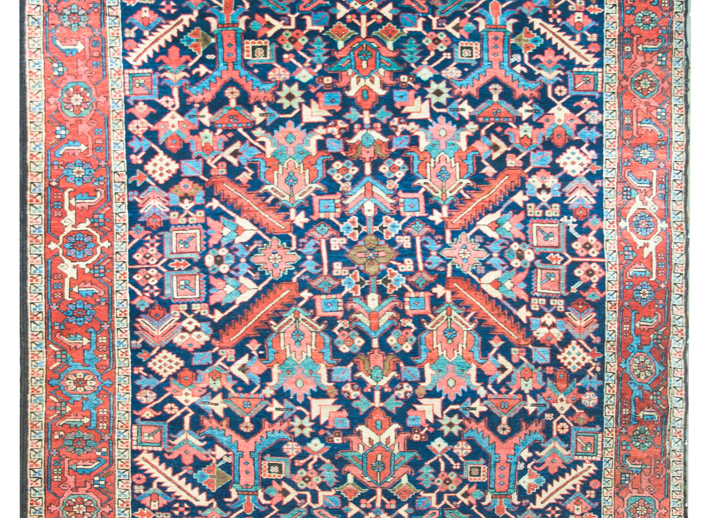 An incredible early 20th century Persian Heriz rug with an all-over mirrored densely woven floral pattern with large-scale flowers and leaves, and myriad stylized flowers, all woven in pink, turquoise, cream, and indigo, and set against a dark