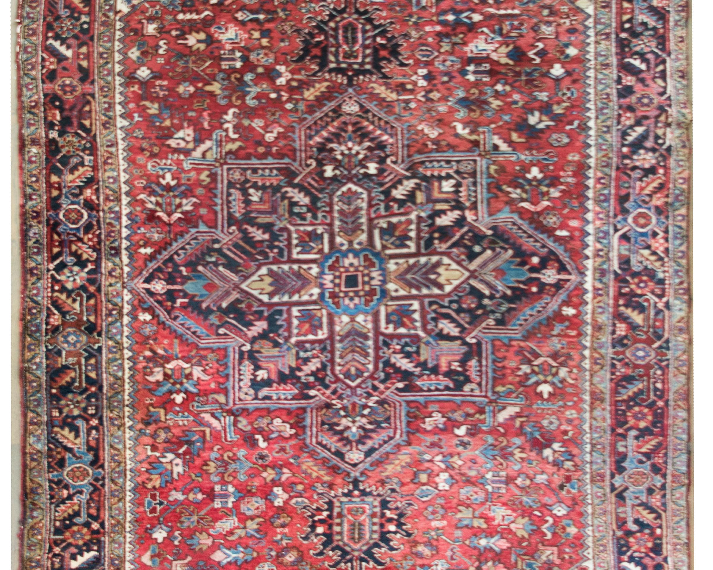 A fantastic large-scale early 20th century Persian Heriz rug with a large stylized central floral medallion woven with an intricate floral and leave pattern, and living admits a field of even more stylized flowers and leaves, and all woven in