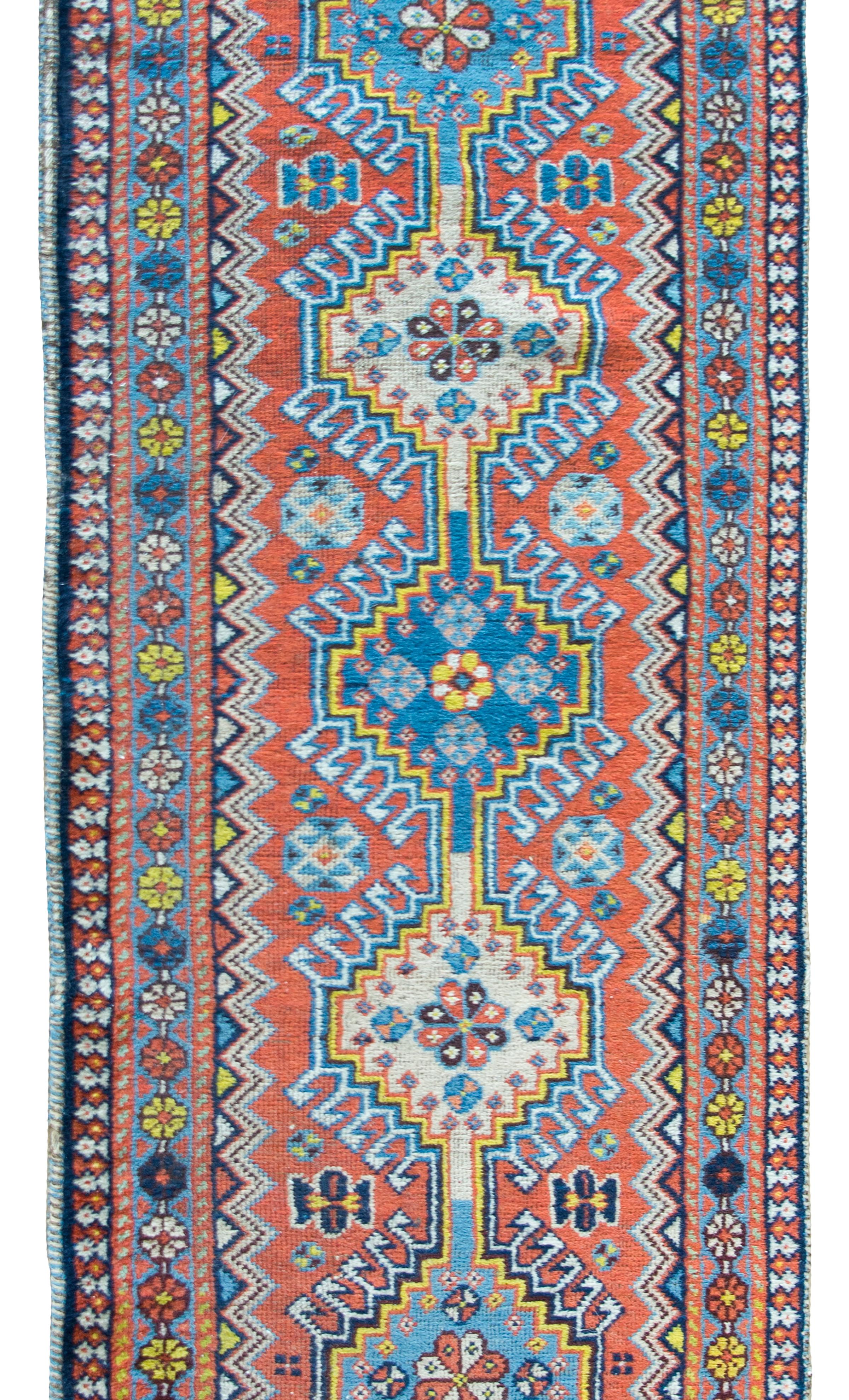 A wonderful early 20th century Persian Heriz runner with five large medallions, each with a stylized floral pattern, living amidst a field of even more stylized flowers, and surrounded by even more stylized flowers, all woven in varying shades of
