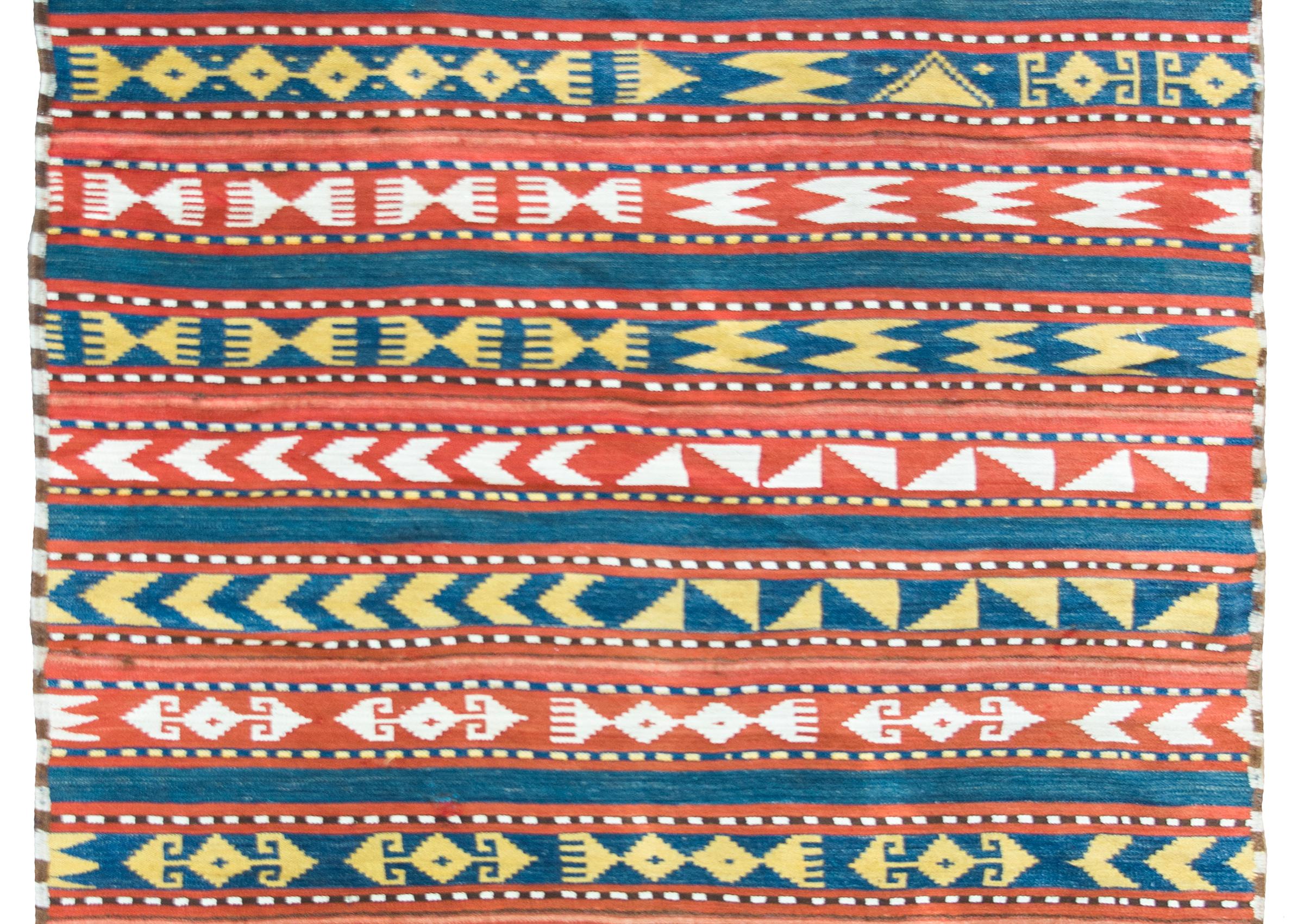 Ein kühner und auffälliger persischer Jajim-Kelimteppich aus dem frühen 20. Jahrhundert, der aus mehreren abwechselnd rot und weiß sowie blau und gelb gemusterten Streifen besteht.