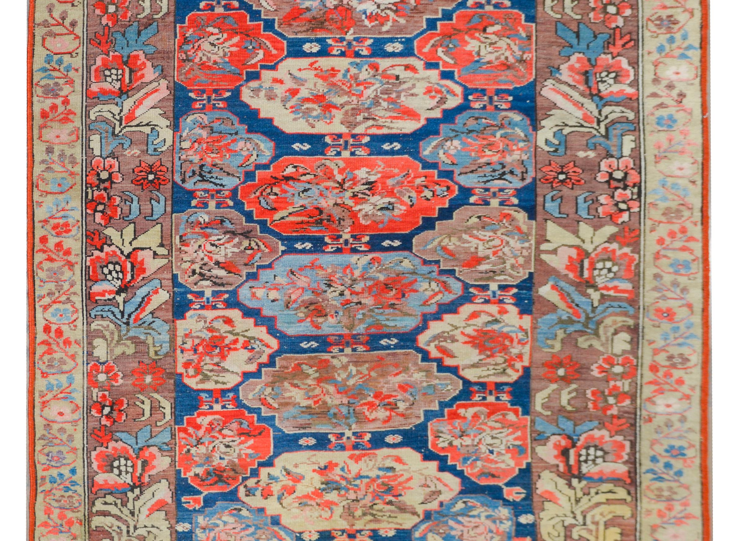 A stunning and rare early 20th century Persian Karabak rug with the most beautiful pattern of floral medallions woven in crimson, cream, indigo, and pink, and set against a dark indigo background. The border is wonderful woven in more floral