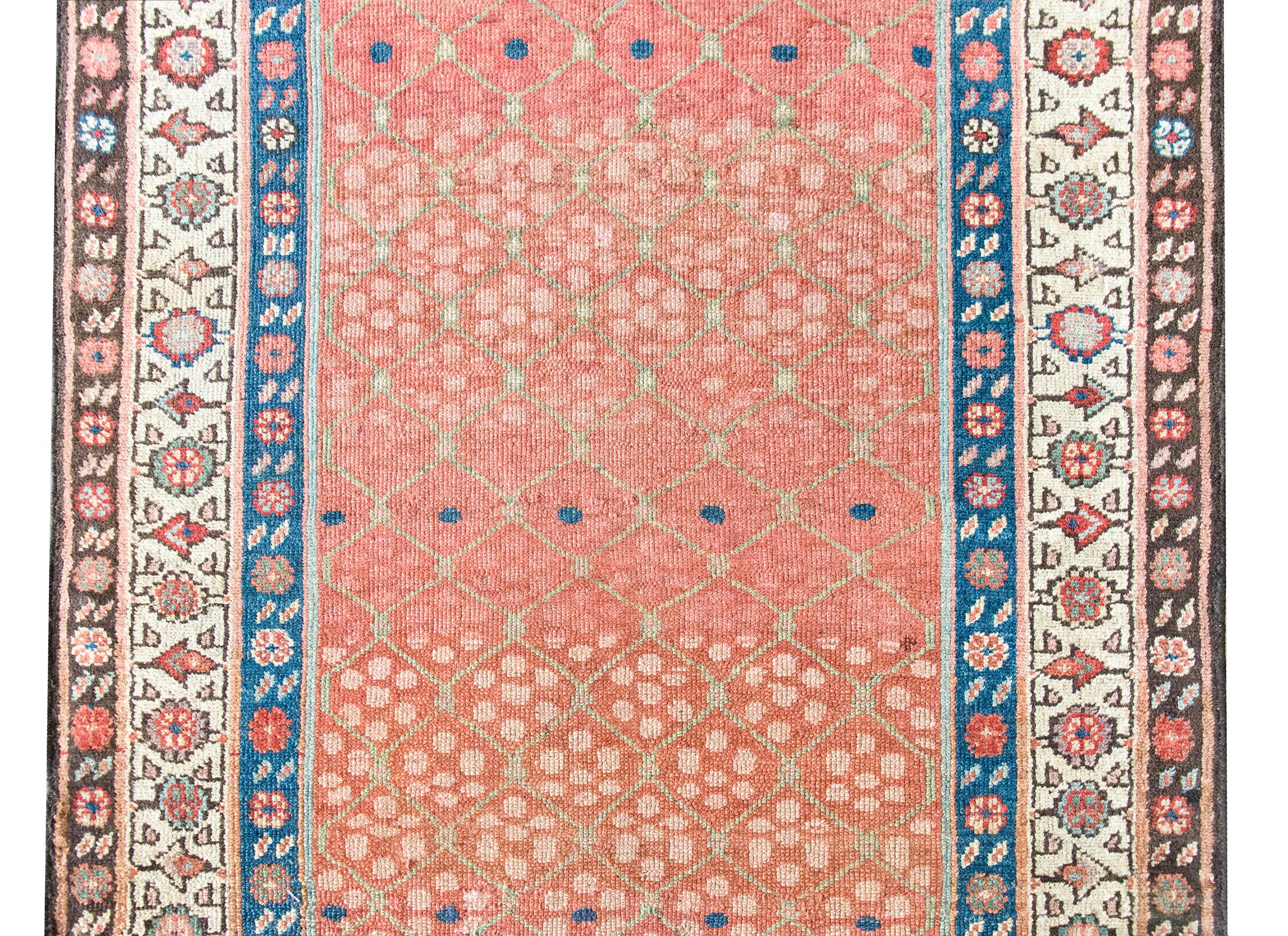 Woven circa 1900, this early 20th-century Persian Karabakh runner is a lyrical example of the region’s romantic, floral aesthetic. The central field is an utter delight—an airy pale green trellis meanders across the length, entwined with stylized