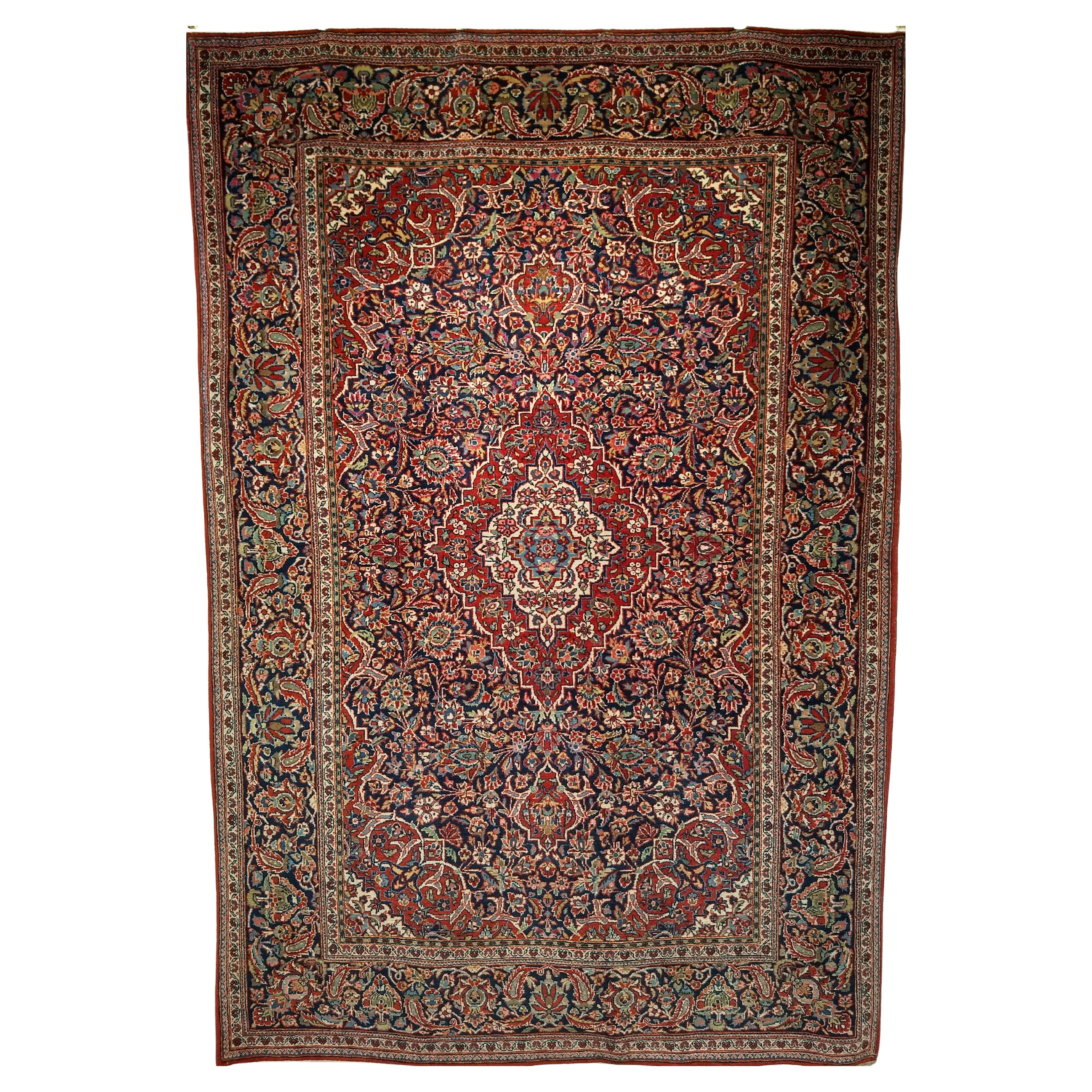 Alfombra persa Kashan de principios del siglo XX con diseño floral en azul marino, rojo y azul