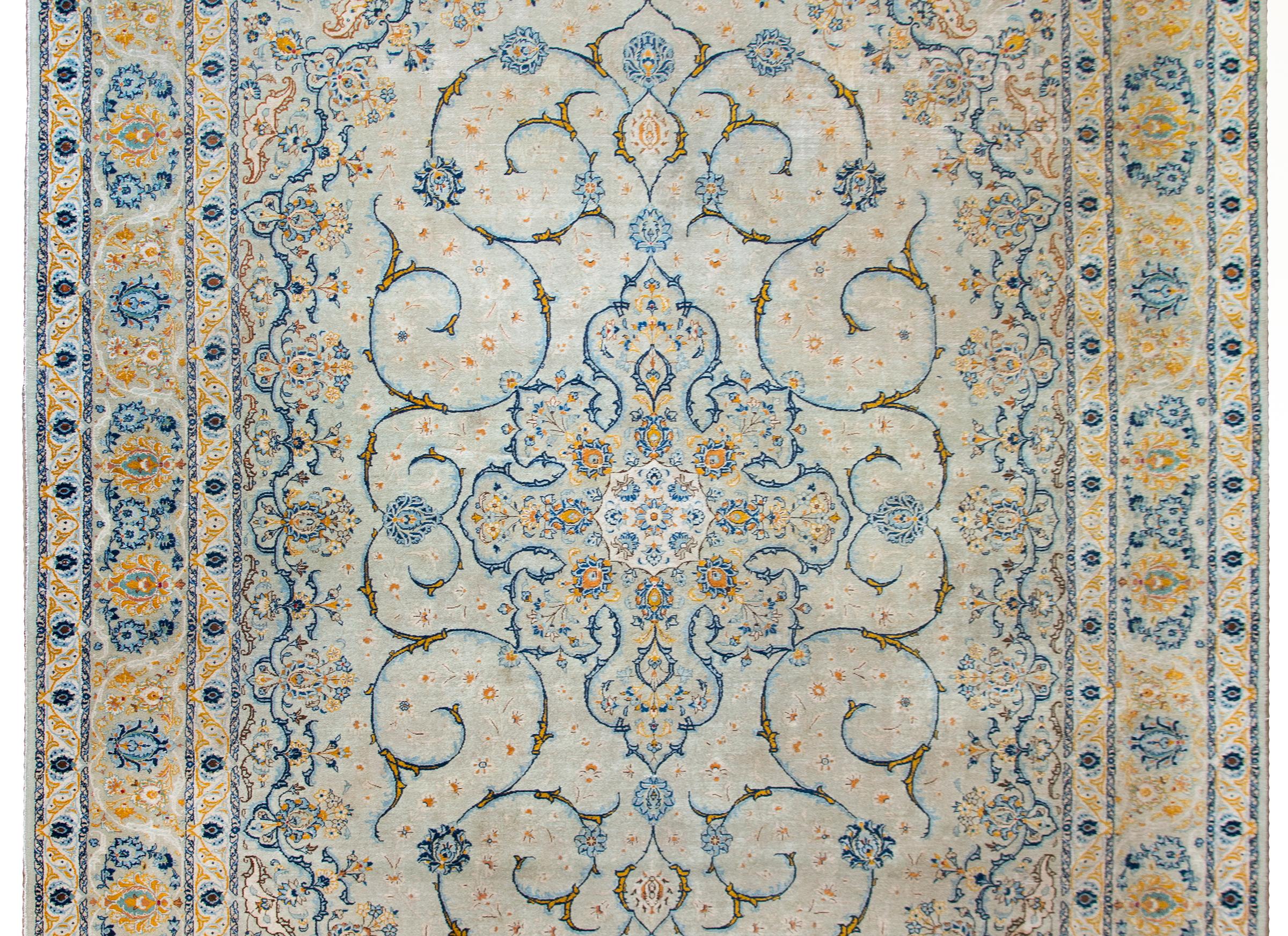A stunning early 20th century Persian Kashan rug with a mesmerizing medallion with stylized flowers and scrolling vines surrounded by an incredible floral patterned border, all woven in brilliant indigos, golds, whites, and reds.