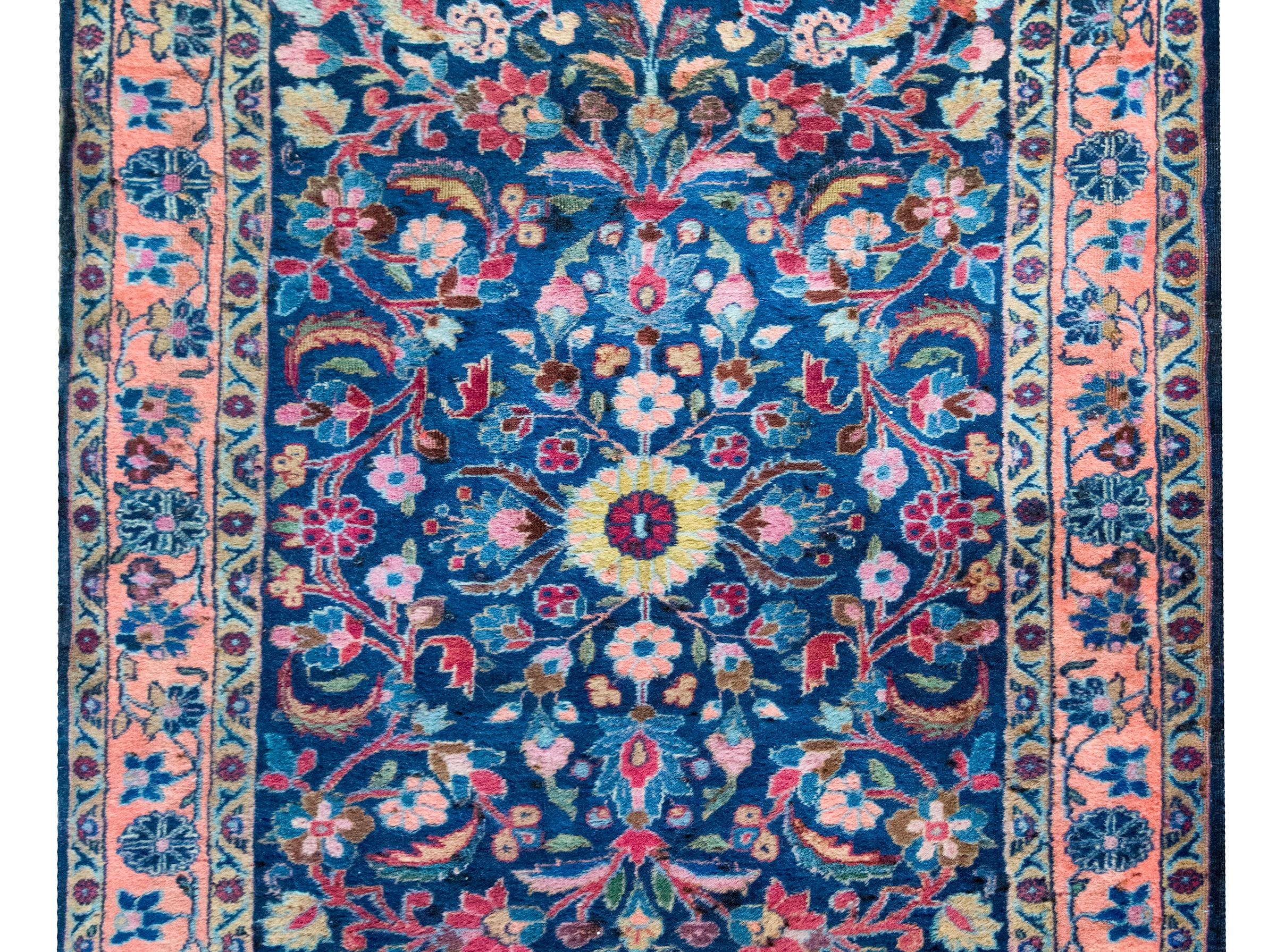Un bellissimo tappeto persiano Kashan dell'inizio del XX secolo con un medaglione centrale a fiori gialli che vive in un campo di altri fiori e viti che scorrono, circondato da un semplice bordo floreale, il tutto tessuto in varie tonalità di lana