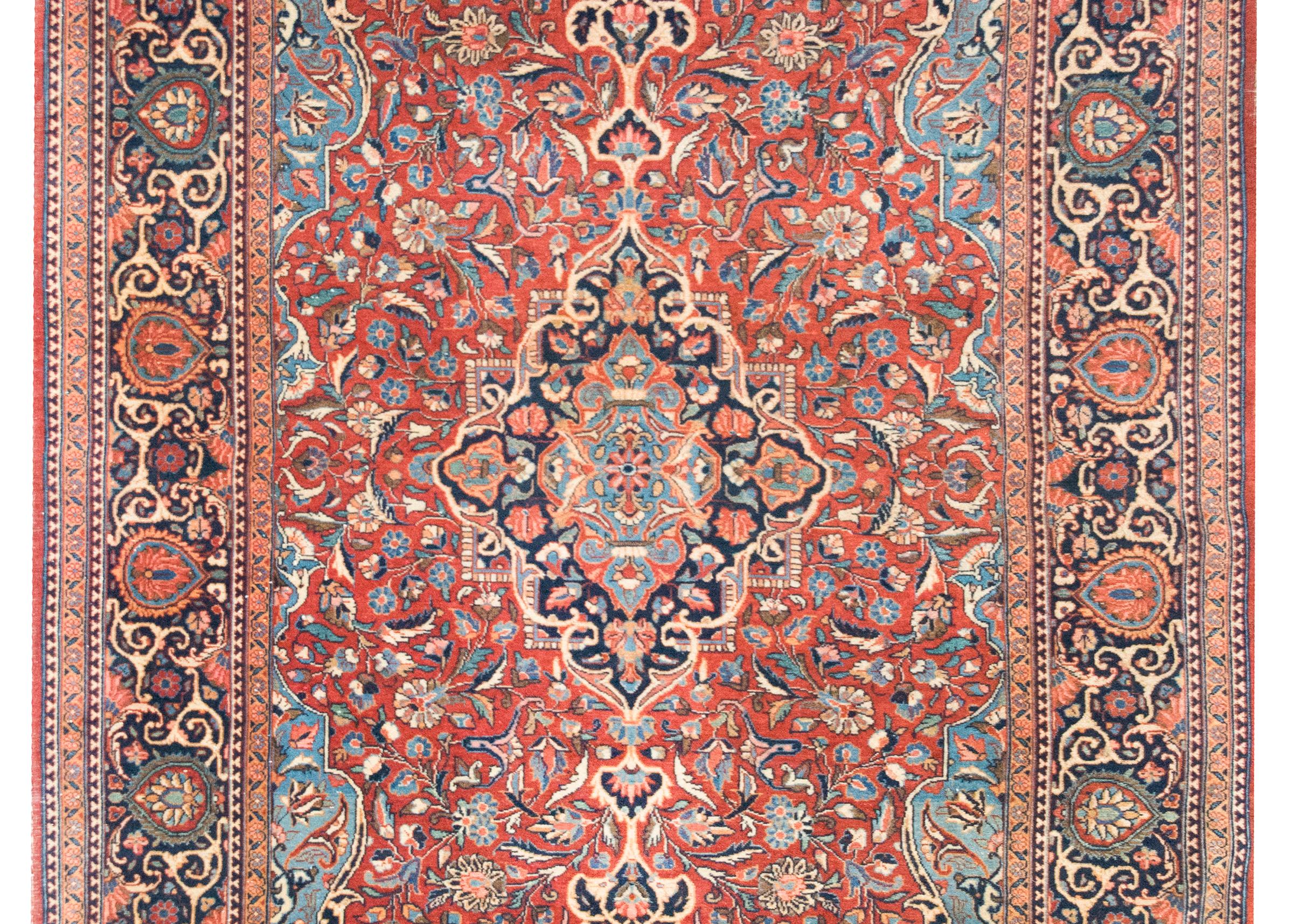 Tessuto intorno al 1900, questo tappeto persiano Kashan dell'inizio del XX secolo è uno splendido esempio di artigianato tradizionale e design ornamentale. Al centro si trova un medaglione floreale riccamente dettagliato, circondato da un campo