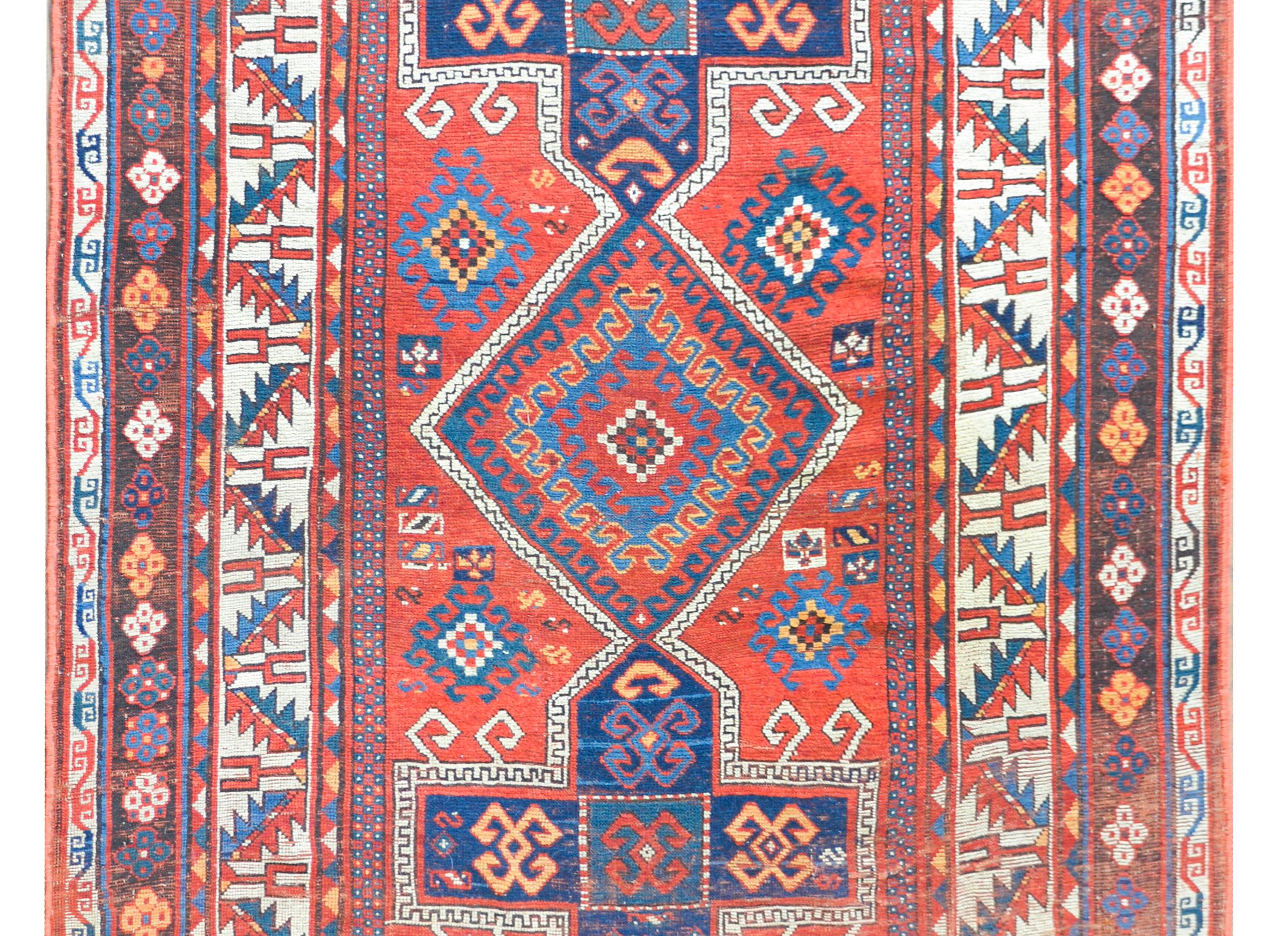 A stunning early 20th century Persian Kazak rug with two large cross and one large diamond medallions with stylized floral and crab patterns, amidst a field of more stylized flowers and goats, all woven in light and dark indigo, teal, gold, and
