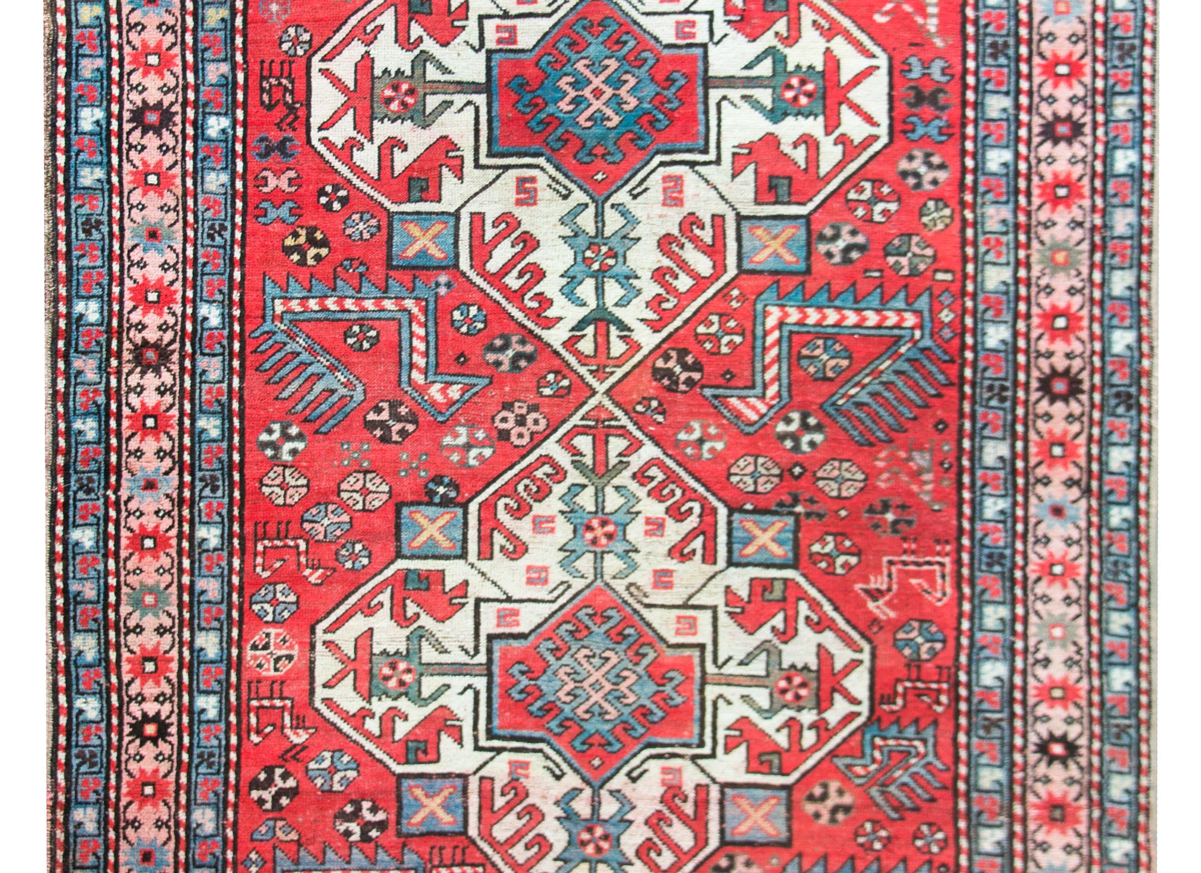 A remarkable early 20th century Persian Kazak rug with the most wonderful pattern containing two large white diamond medallions with stylized floral patterns amidst a field of more stylized flowers, goats, and large chickens, all woven in crimson,