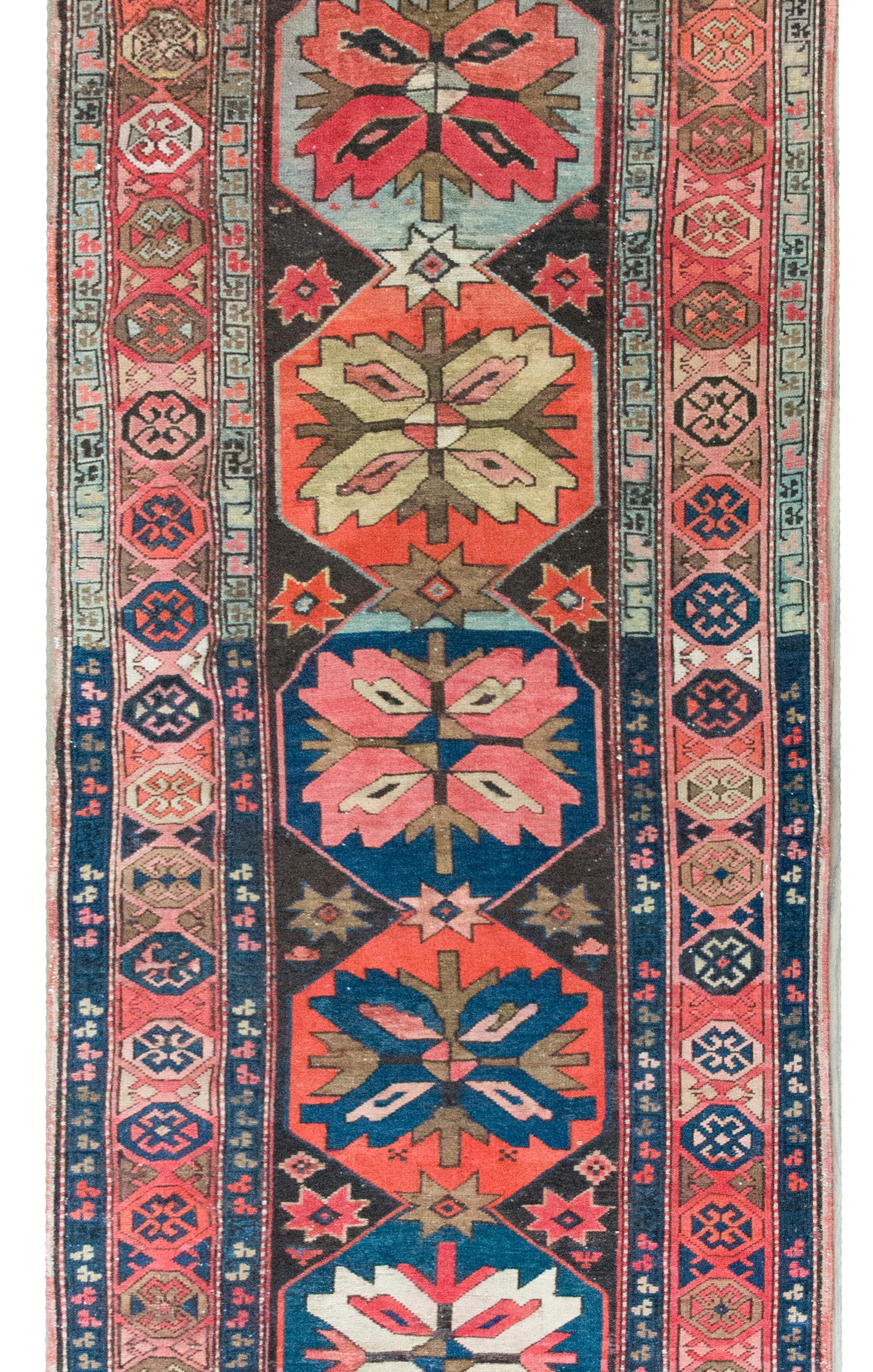 Un notevole tappeto persiano Kazak dell'inizio del XX secolo con i più meravigliosi medaglioni floreali che corrono per tutta la lunghezza del tappeto, ciascuno tessuto in colori diversi e circondato da un bordo con fiori ancora più stilizzati e