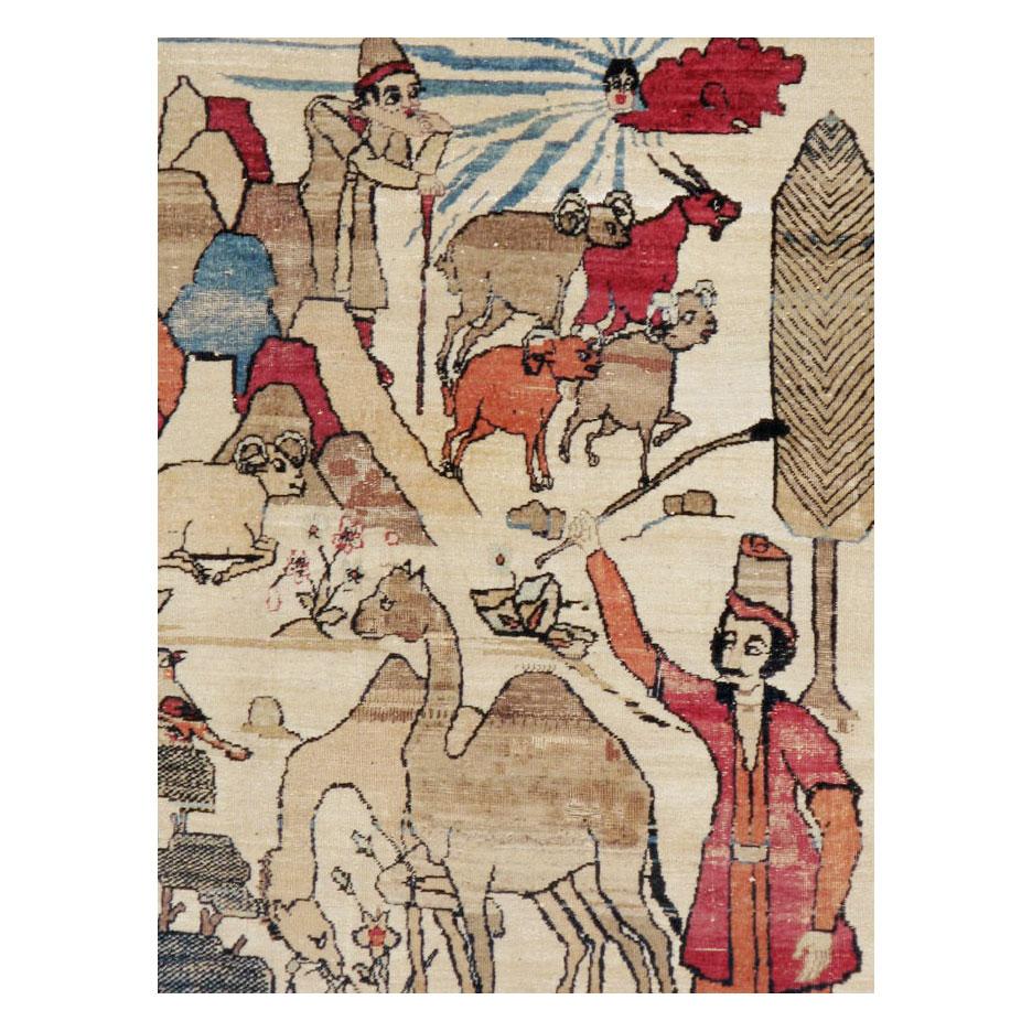 An antique Persian Kerman accent rug handmade during the early 20th century. The urban workshop weavers of Kerman considered the lifestyle of their tribal counterparts when designing this pictorial rug. The design reveals the lifestyle of the many