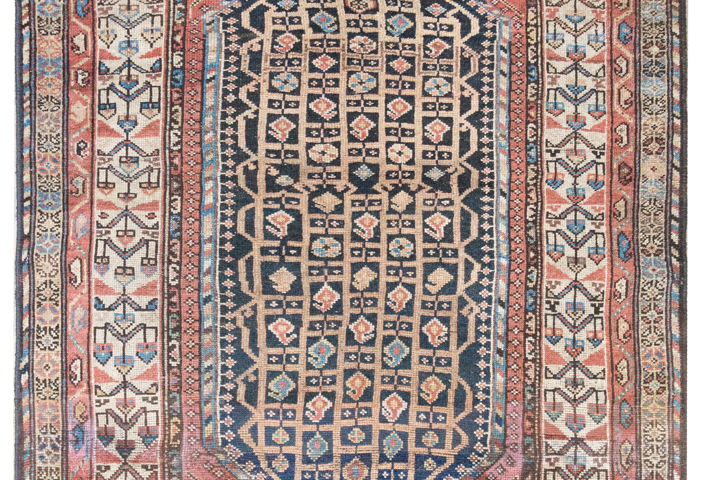 Woven around 1900, this early 20th-century Persian Khamseh rug showcases the geometric elegance and folk charm characteristic of the tribal weavings of southwestern Iran. At its center is a striking six-sided medallion, filled with a delicate grid