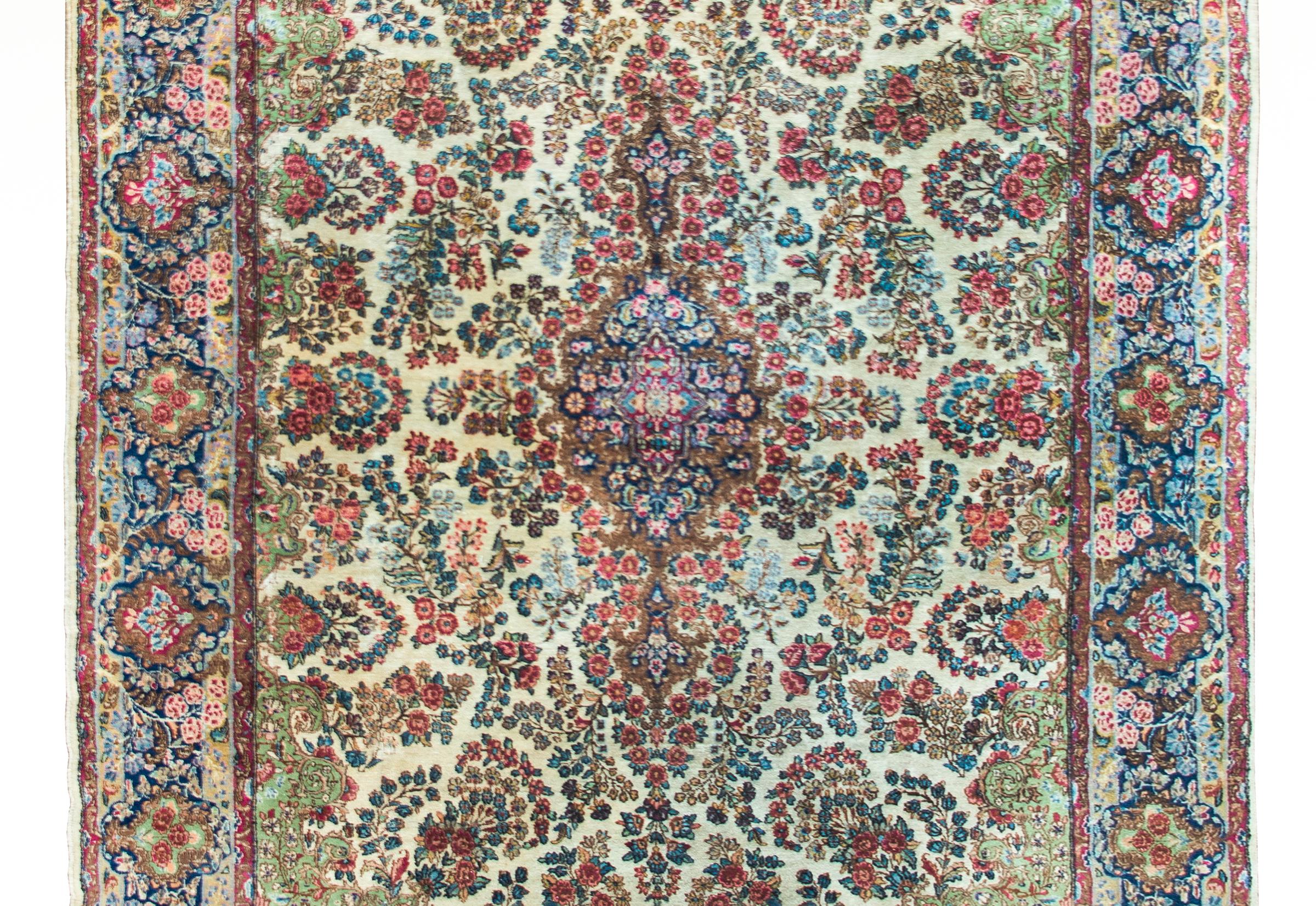 Uno splendido tappeto persiano Kirman dell'inizio del XX secolo con un medaglione floreale centrale con un motivo floreale a gradini con una miriade di fiori che si irradiano dal centro e riempiono un campo con fiori e foglie ancora più stilizzati. 