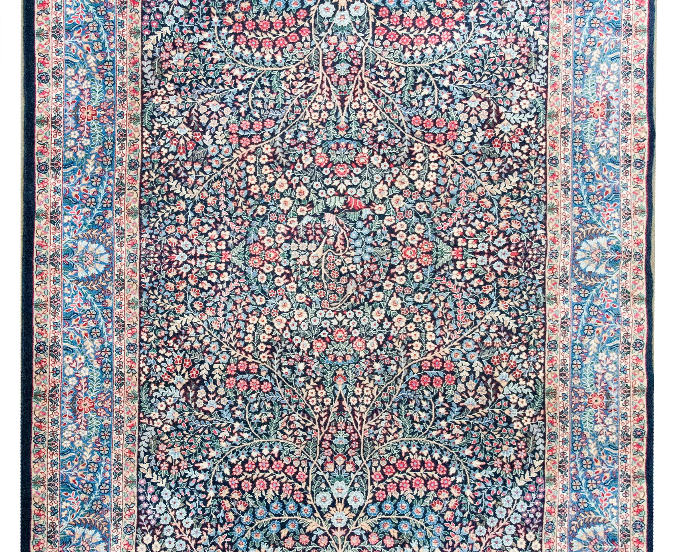 Uno splendido e raro tappeto persiano Kirman dell'inizio del XX secolo con un elaboratissimo disegno con una miriade di alberi vorticosi e viti fiorite che culminano con due uccelli seduti sui rami superiori che terminano al centro del tappeto.  Il