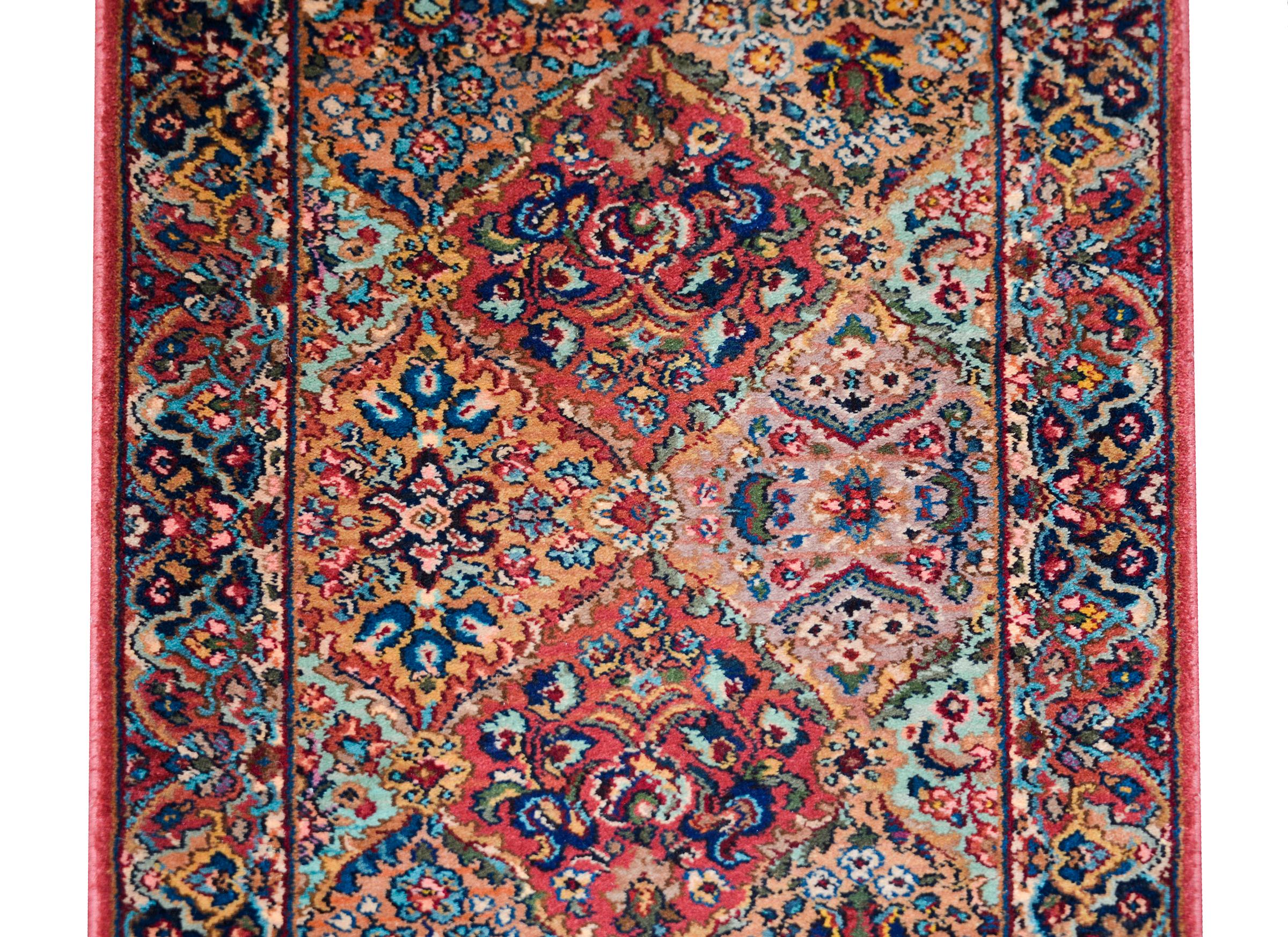 A striking early 20th century Persian Kirman runner with the best pattern in pattern containing myriad diamond medallions hidden amidst myriad flowers and scrolling vines, and surrounded by a complementary floral patterned border.