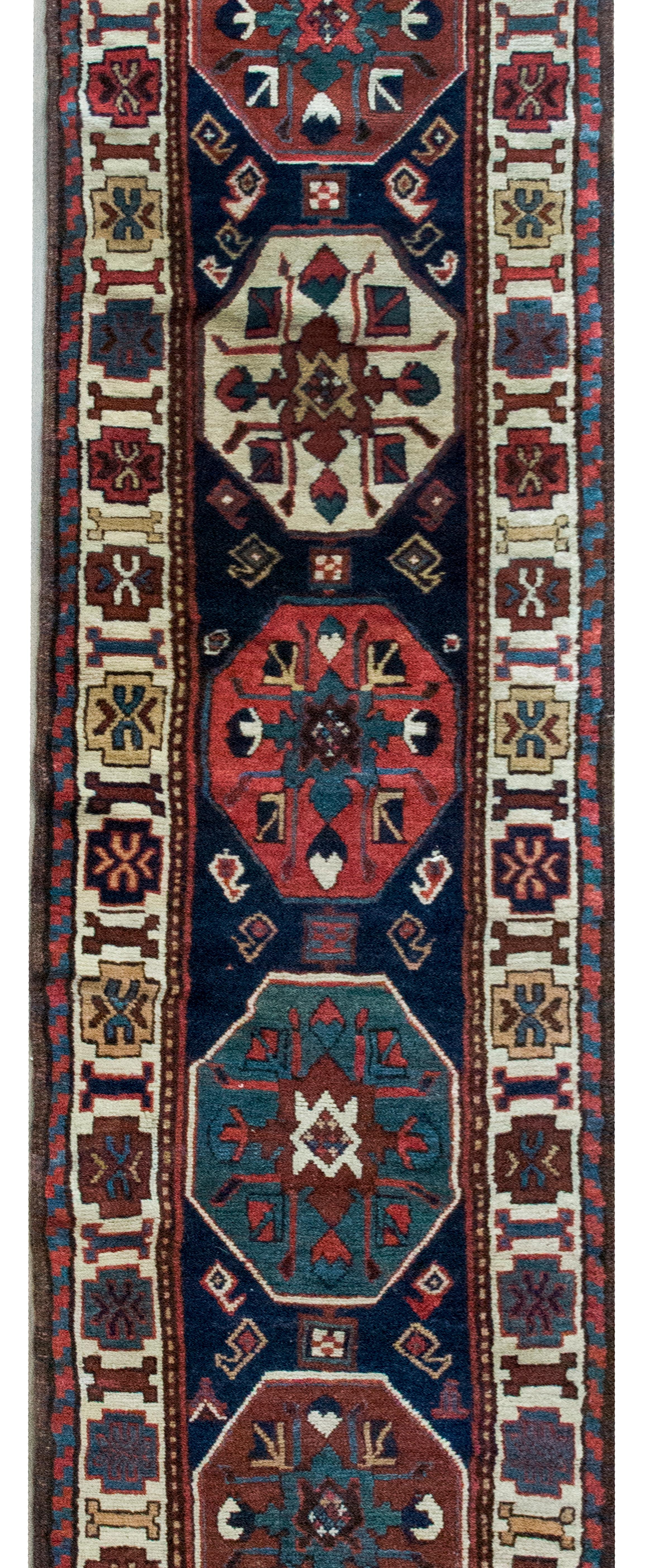 Dieser bemerkenswerte persische Kuba-Läufer aus Aserbaidschan aus dem frühen 20. Jahrhundert ist ein lebendiges Beispiel für traditionelle Handwerkskunst und Design. Im Mittelpunkt der Komposition stehen sieben achteckige Medaillons, die jeweils mit